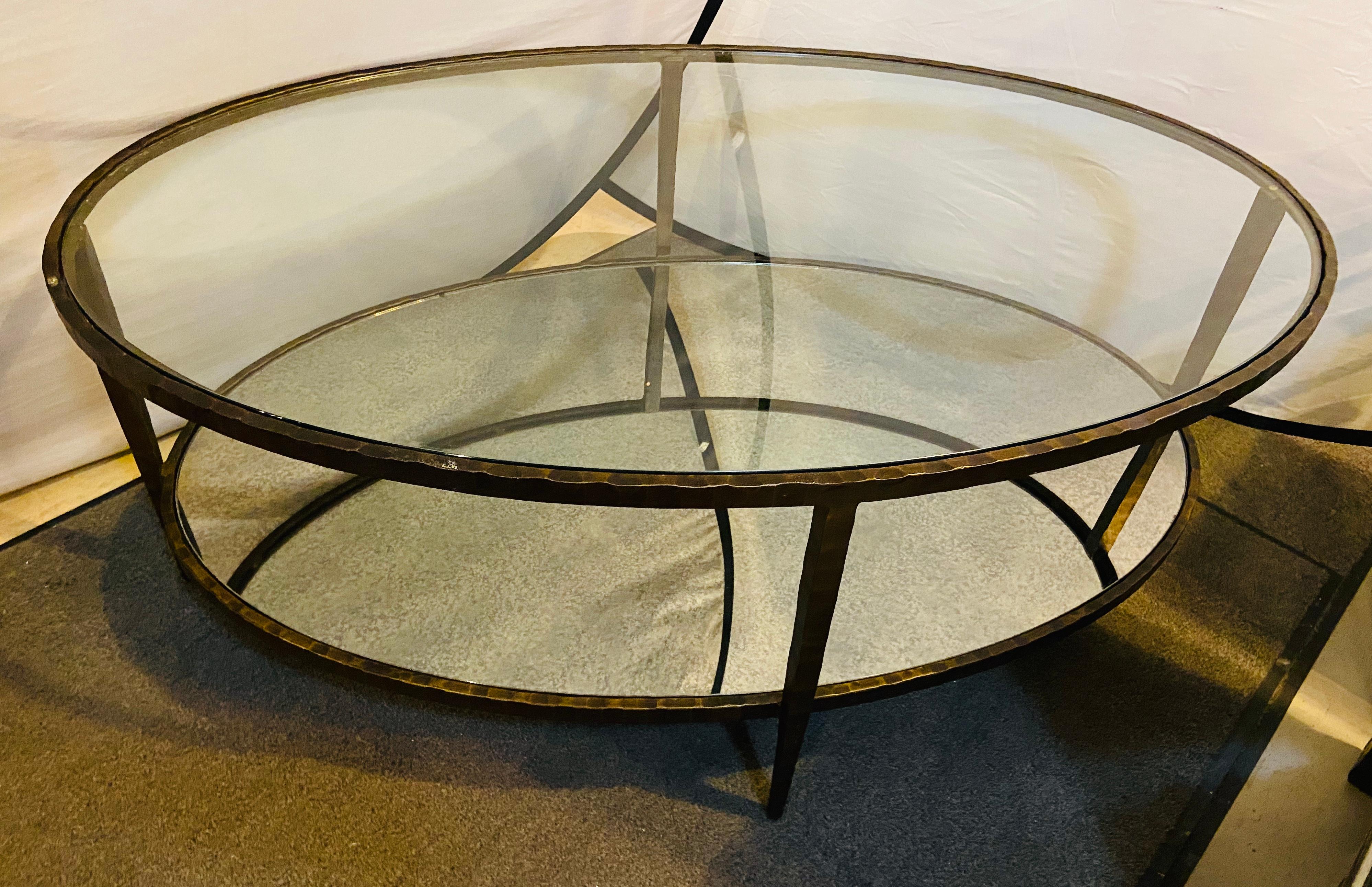 An oval antiqued metal coffee / low table.
The table features a glass top and a distressed mirror lower shelve. This Hollywood Regency style table will certainly add style and sophistication to your living environment.
  
