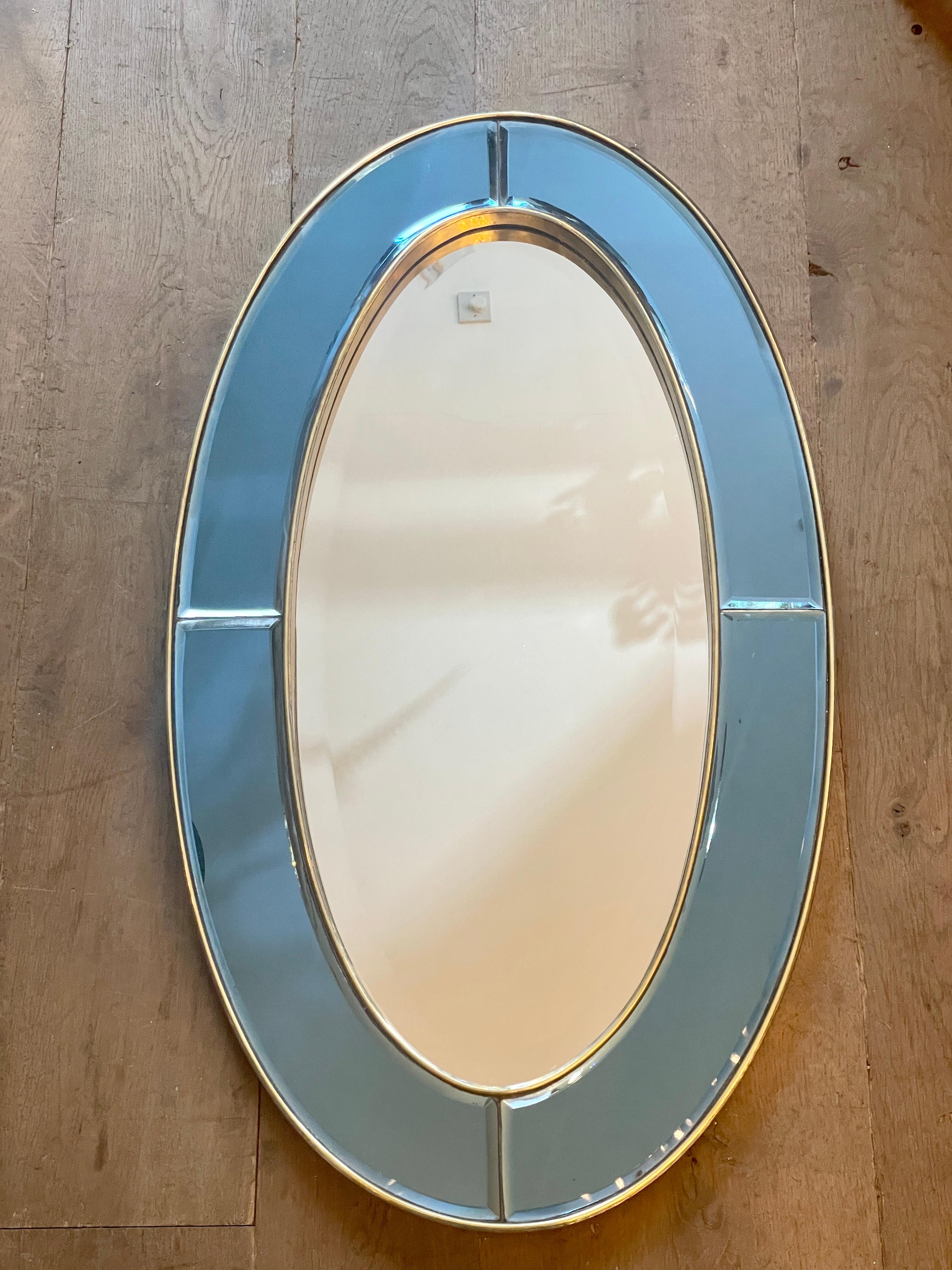 An oval brass framed mirror with a panelled blue mirrored border, all with bevelled edges, and a clear bevelled mirror interior. Lightly distressed, with nice patina to brass. Very much in the Italian 50's taste. Five available.

Contemporary.