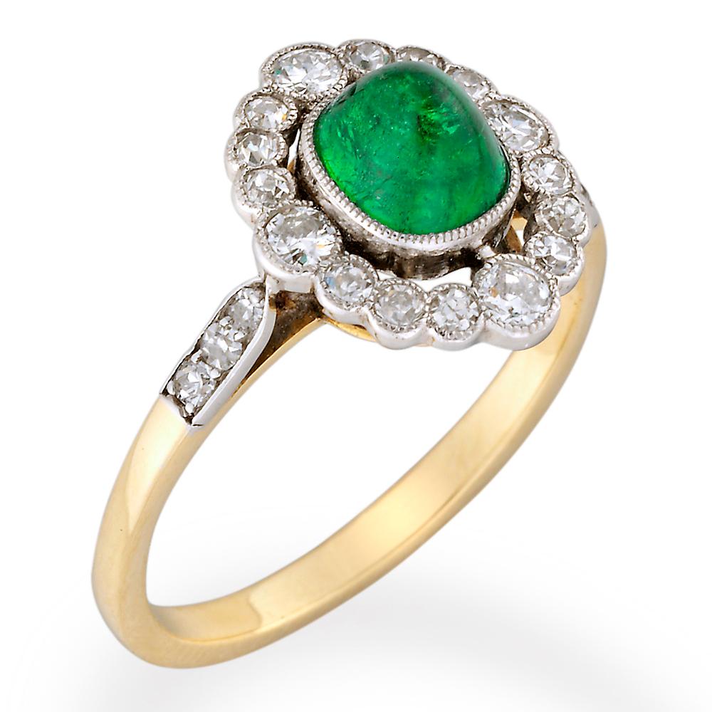 An oval emerald and diamond cluster ring, the central oval cabochon-cut emerald estimated to weigh 1.35 carats, millegrain-set within an open surround of sixteen round brilliant-cut diamonds, all millegrain-set in white gold to a yellow gold mount,