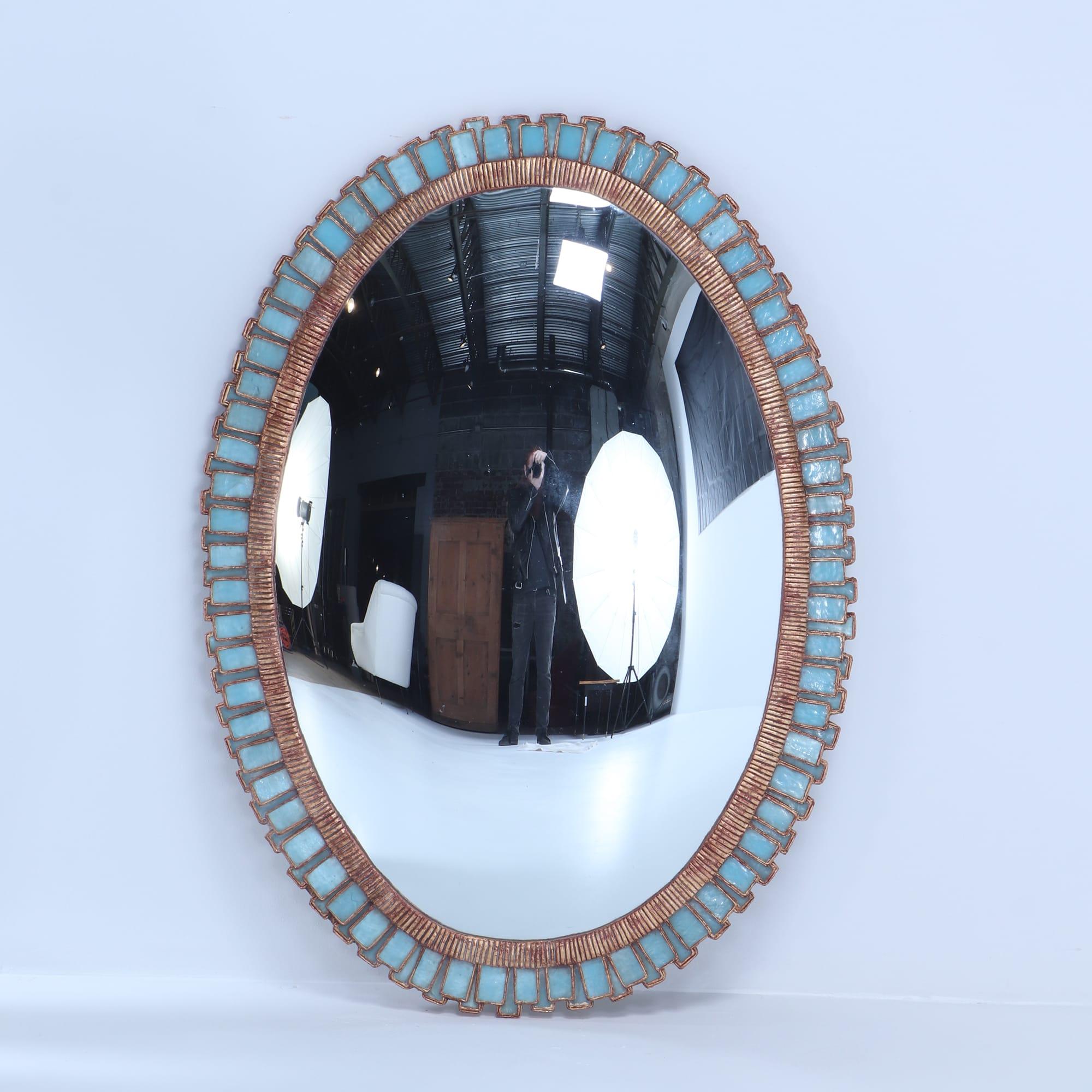 An oval mirror made of gilt resin and blue glass in the manner of Line Vautrin. Contemporary. These mirrors are hand made by an artist and may be made to order.