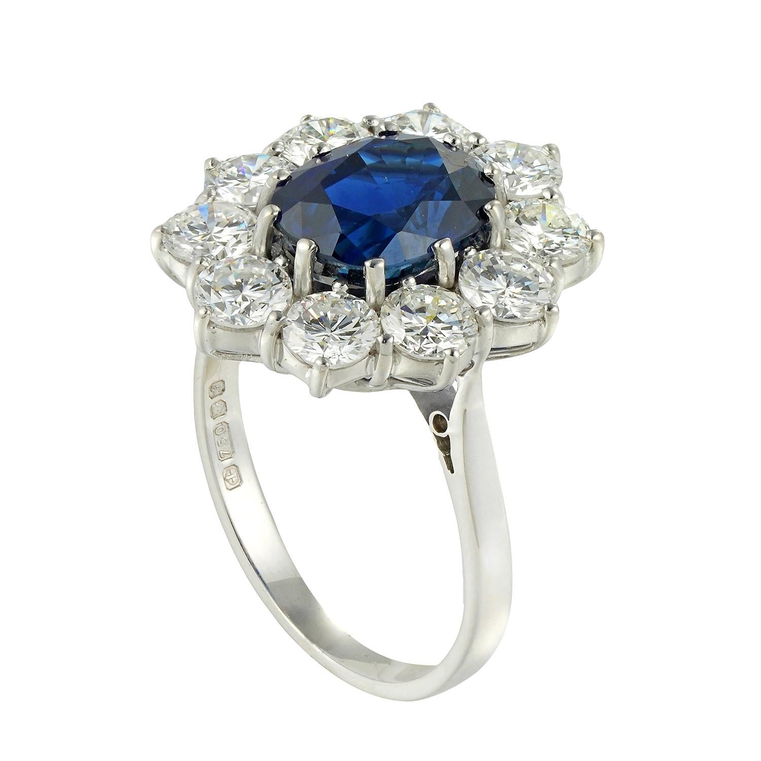 An oval sapphire and diamond cluster ring, the oval faceted sapphire weighing 3.74 carats accompanied by GCS certificate, stating to be a natural sapphire with no indications of heating, claw-set to the centre of a cluster surround of ten round