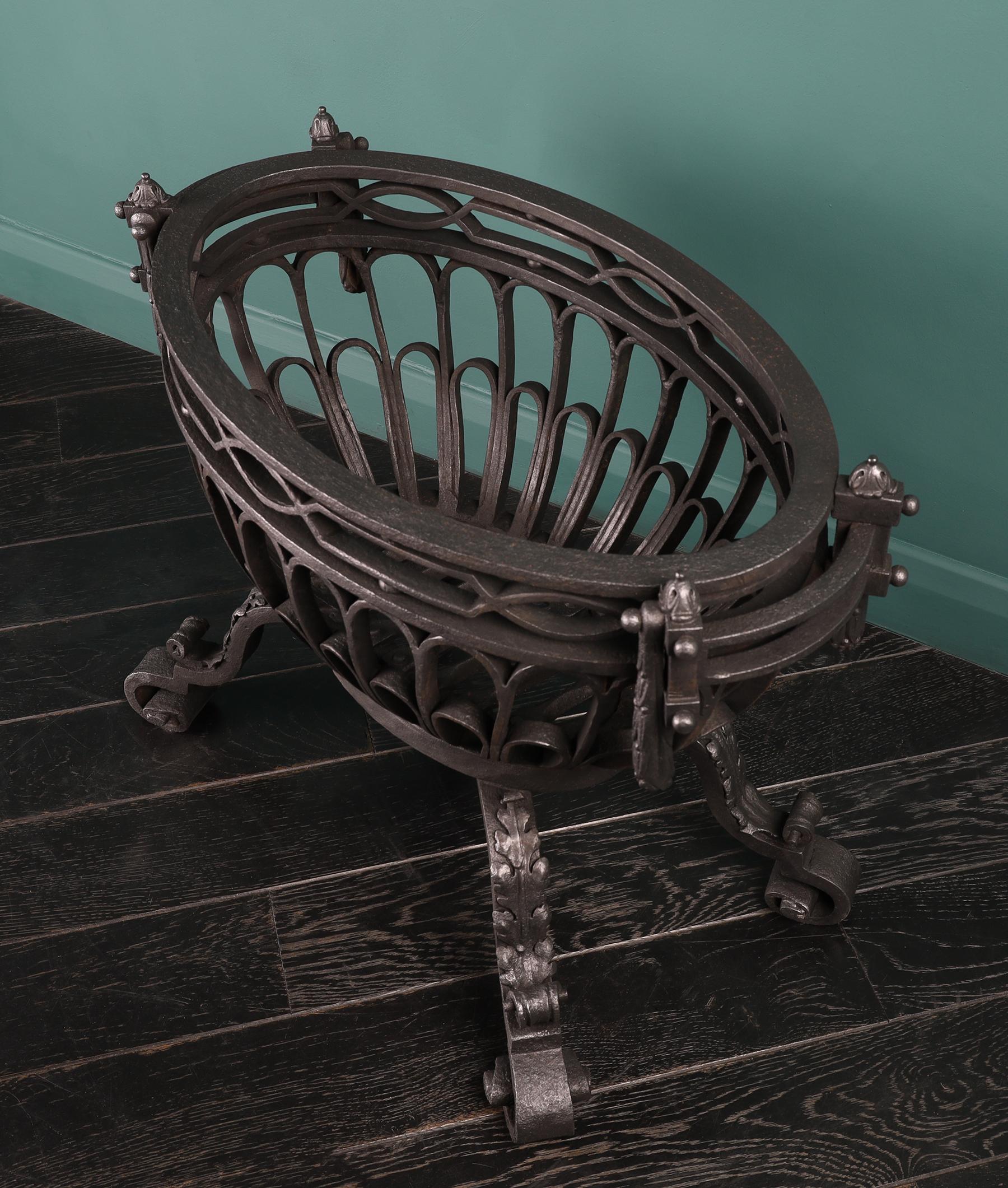A beautifully constructed oval wrought iron fire grate of brazier form set on four repousse adorned scrolled legs. Reed and berry drop handle detail. Finished in black graphite.

Circa Mid-19th Century.