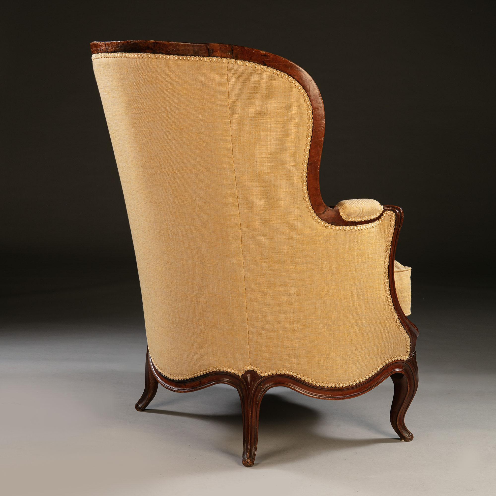 An overscale pair of 19th century walnut bergères or armchairs, with curved backs, curved seat rails and out swept arms. Now upholstered in a sand colored linen with braid.