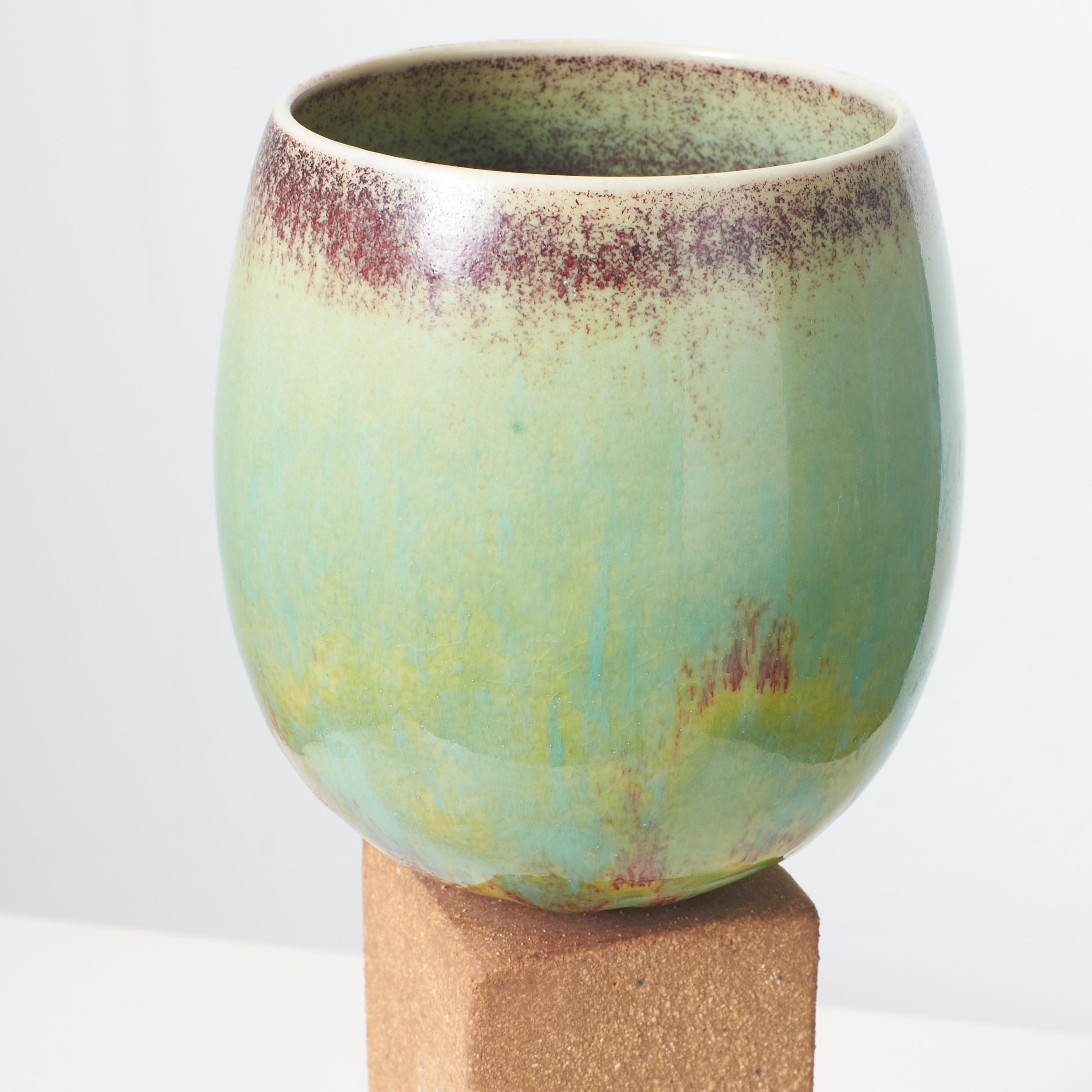 An ovoid vase with green glaze on tall stone base by Stig Lindberg 1