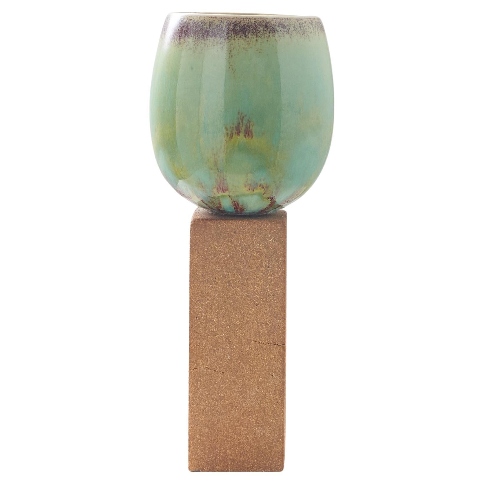 An ovoid vase with green glaze on tall stone base by Stig Lindberg