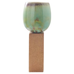 An ovoid vase with green glaze on tall stone base by Stig Lindberg