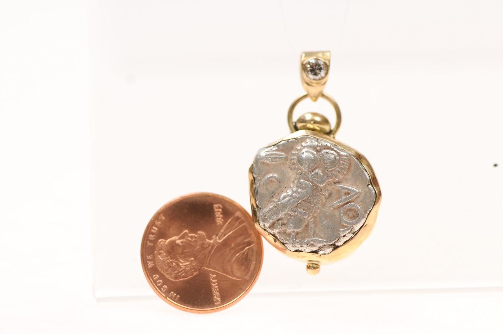 An Archaic Style AR Tetradrachm [coin] minted in Attica, Athens, Circa 353-294 BC. This ancient Greek coin has been fixed in 18 karat gold trim with a diamond as a substantial pendant piece. On the obverse side of the coin, the profile of Athena, on