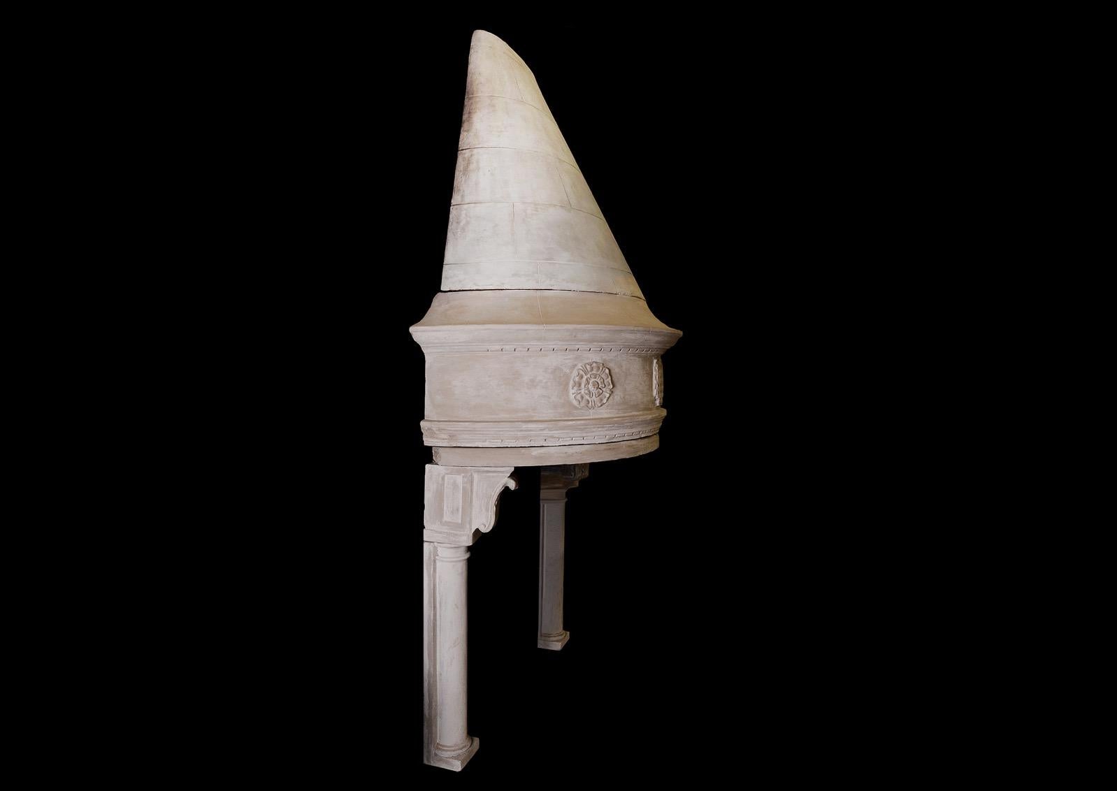 An impressive and unusual cast stone fireplace. The jambs with half round columns, surmounted by carved corbels. The semi-circular frieze with rosettes and portcullis adornments, surmounted by tapering hood. Distressed finish to stone.

Measures: