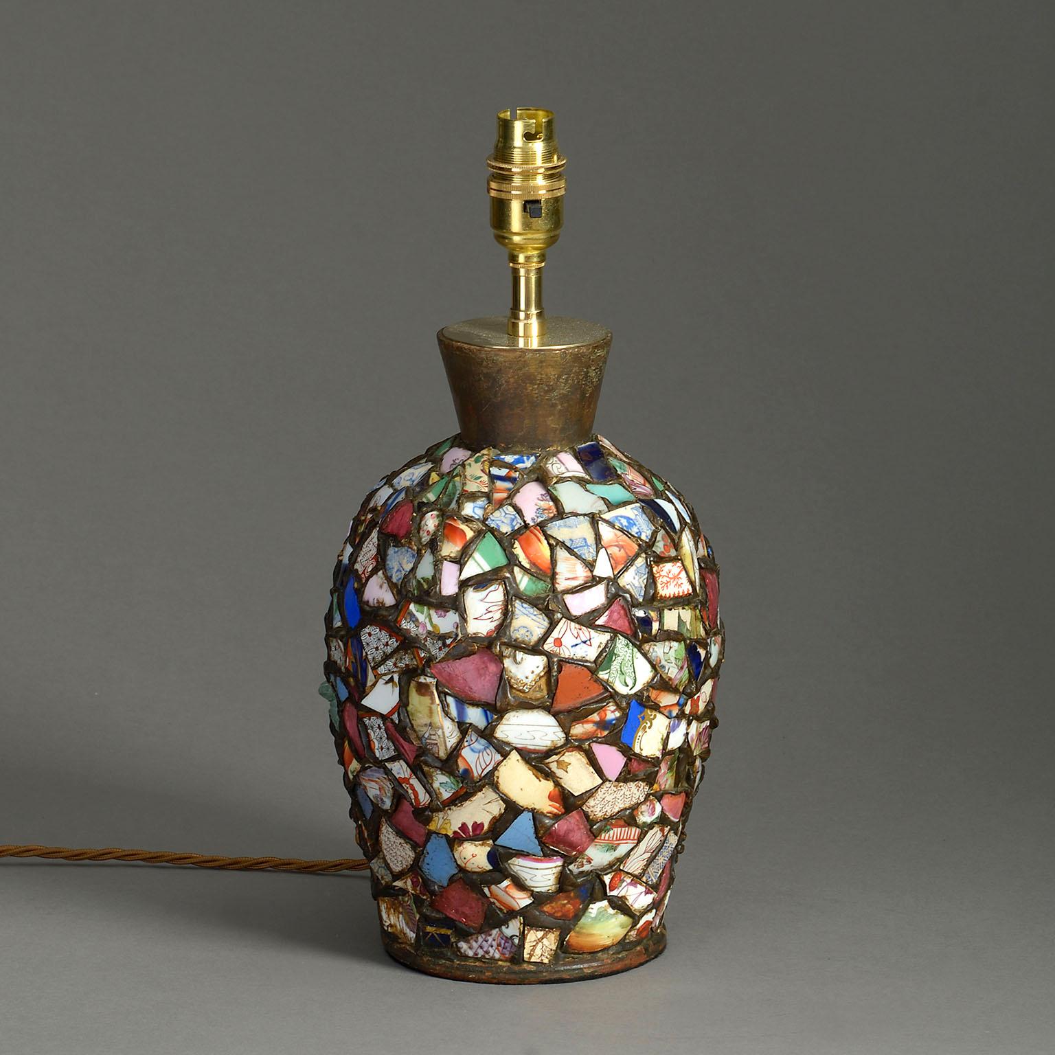 Eine höchst ungewöhnliche Tischlampe, deren Korpus aus einer Collage zerbrochener Porzellanfragmente besteht, die zumeist aus dem späten achtzehnten Jahrhundert stammen und aus China stammen.

Die Abmessungen beziehen sich auf die Vase.

Schirm