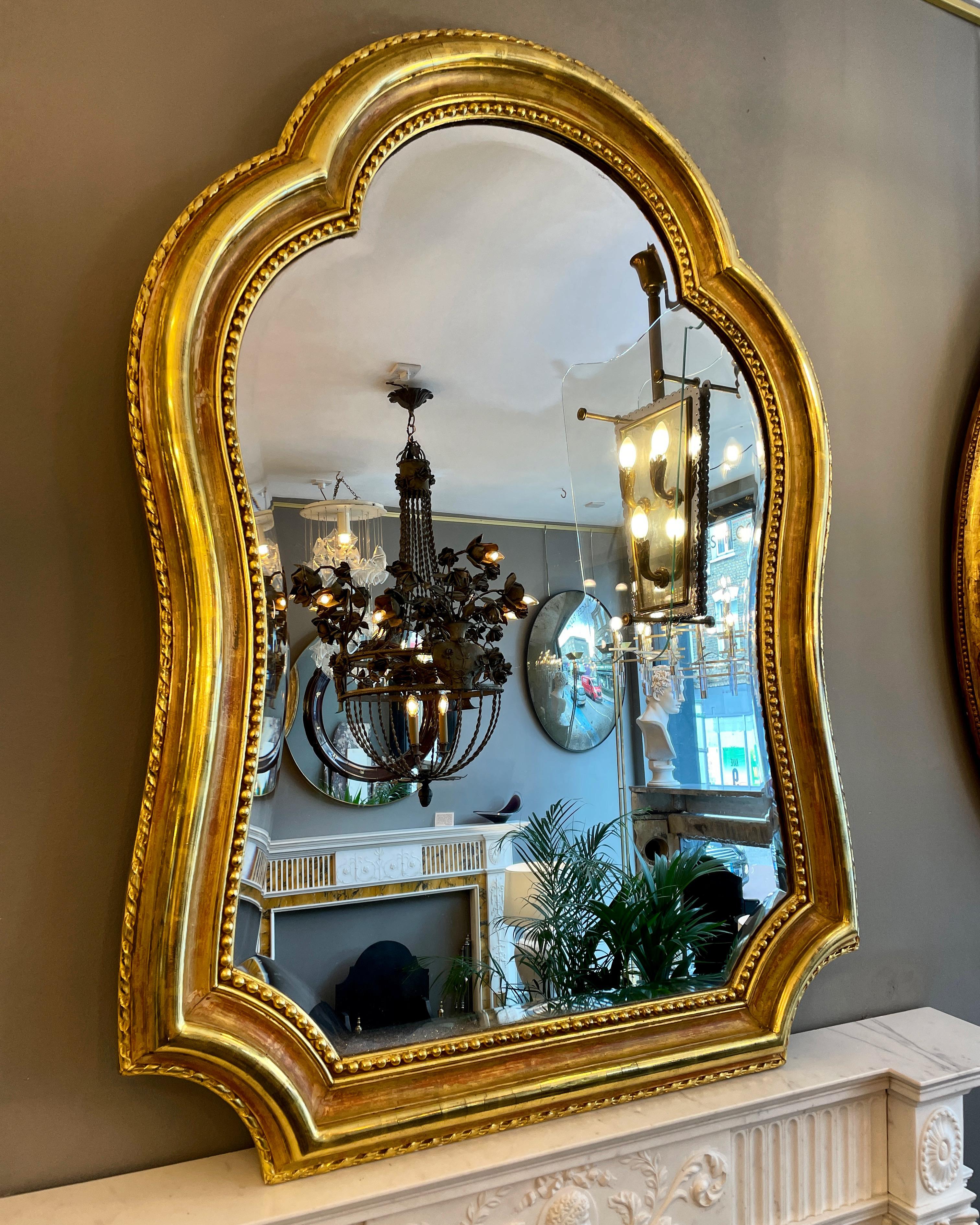 An unusual gilt French mirror with quality gilt work, rich in colour and in very good condition. Original bevelled plate. The frame with a wide moulding, outer edge with ribbon detail and inner beaded mirror border. A quality piece. Mid to late 19th