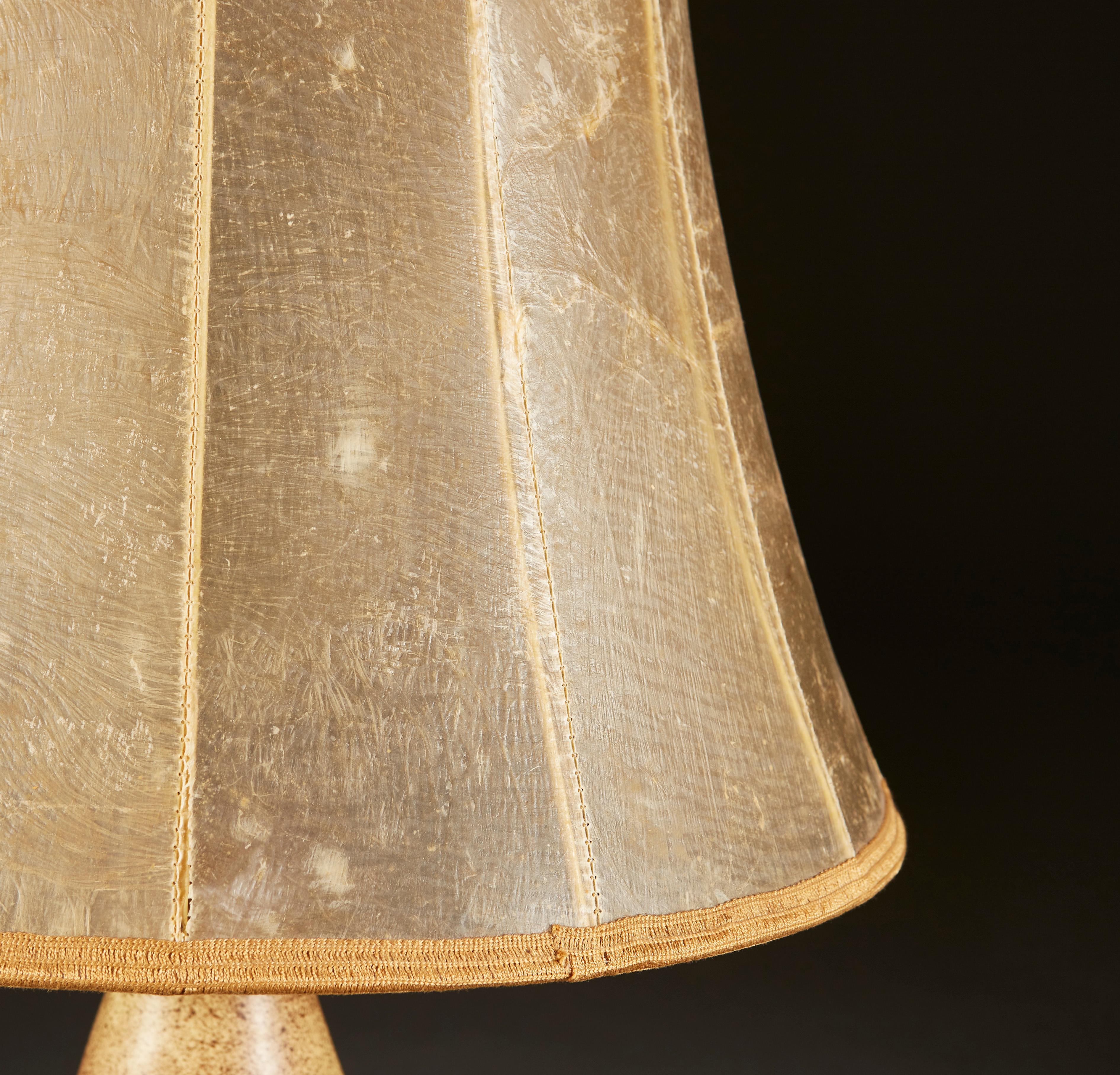 Une lampe de table inhabituelle en poterie d'art du milieu du vingtième siècle, à glaçure salée, avec six petits bras sur le corps. La lampe porte une signature à la base. 

La lampe est accompagnée d'un abat-jour en parchemin antique. 

La
