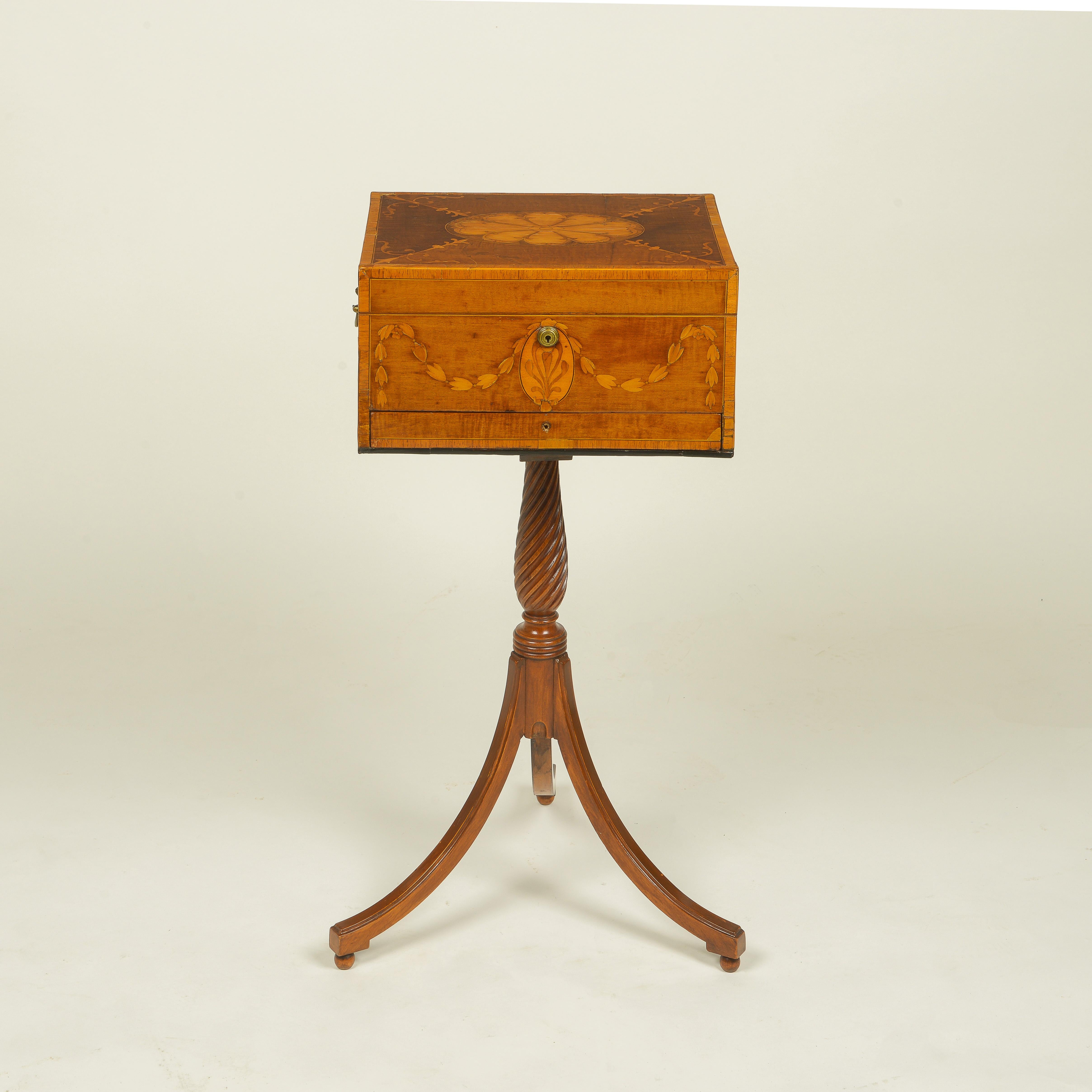The table top in the form of a rectangular box finely inlaid with an oval flowerhead centered by bellflower spray spandrels; the sides inlaid with bellflower garlands and brass carrying handles to the sides; raised on a spiral-fluted columnar
