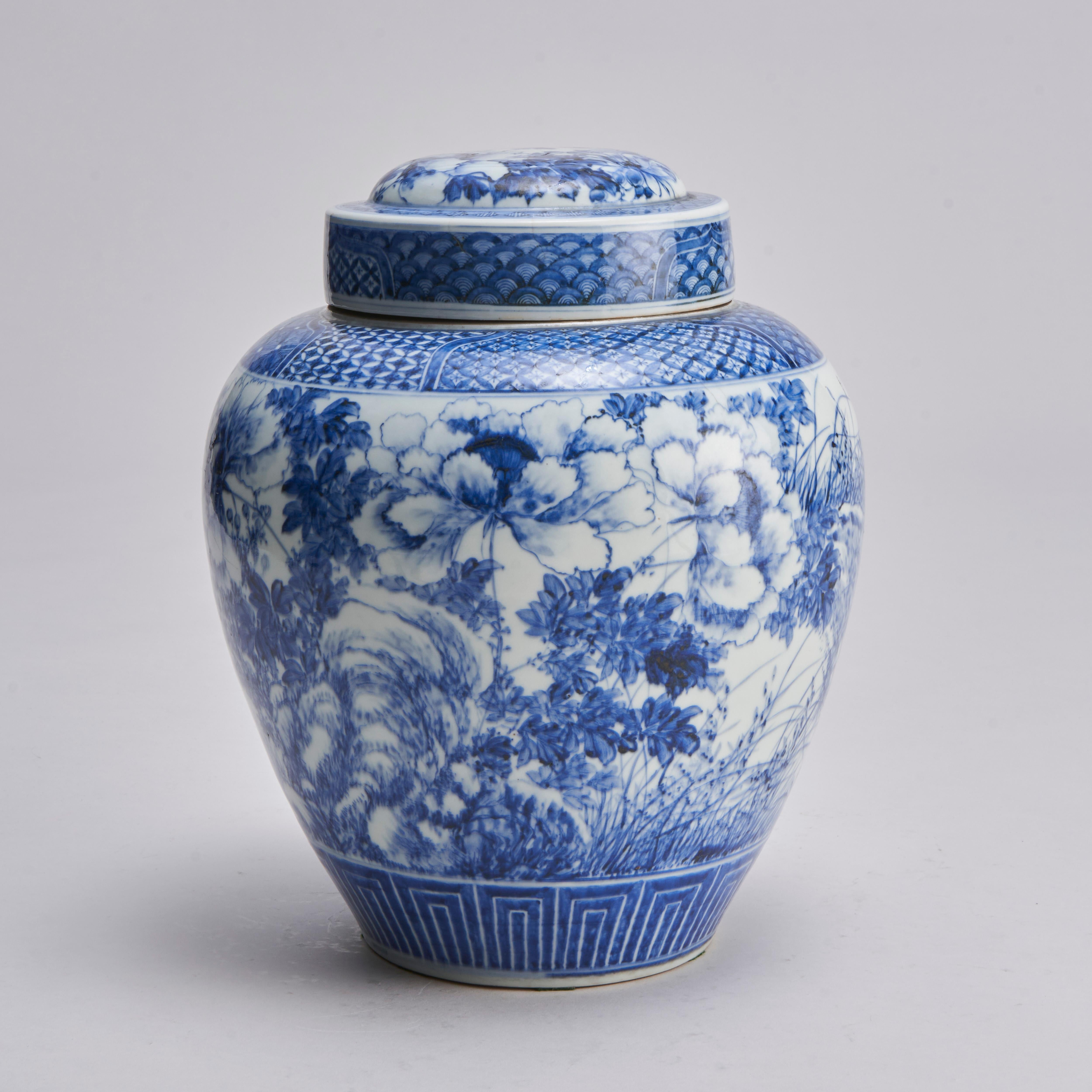 A rare example of a 19th century Japanese blue and white ginger jar with original cover and inner stopper with decorative peach knop.

The vase itself decorated with flowing images of large blossoming peonies and swaying grasses. The neck with a