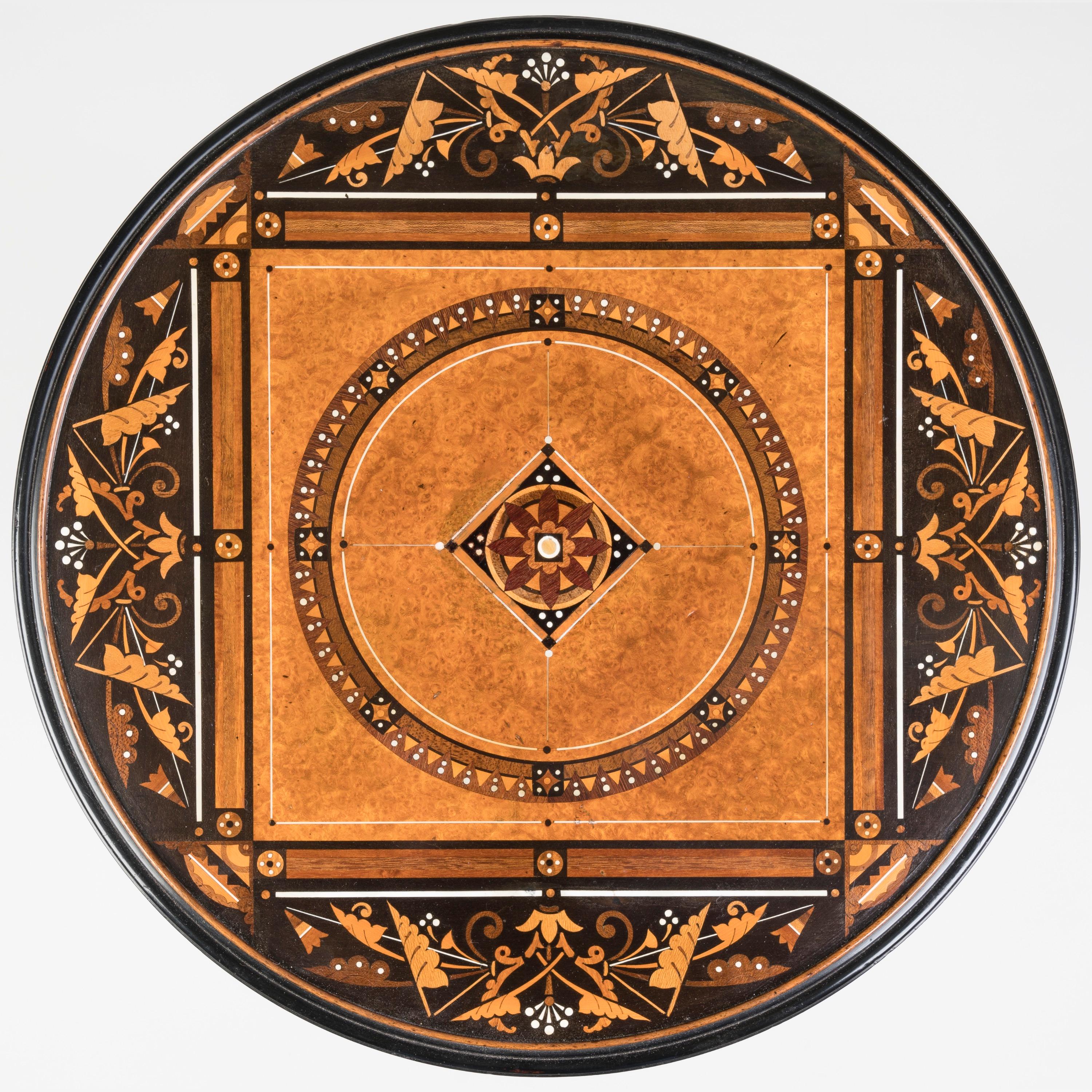 Table à plateau en marqueterie
Attribué à Jackson & Graham

Probablement conçu par Bruce James Talbert (1838-1881)

Le plateau circulaire est incrusté d'une pléthore d'échantillons de bois et d'os, consistant en un quadrangle d'amboyna orné de