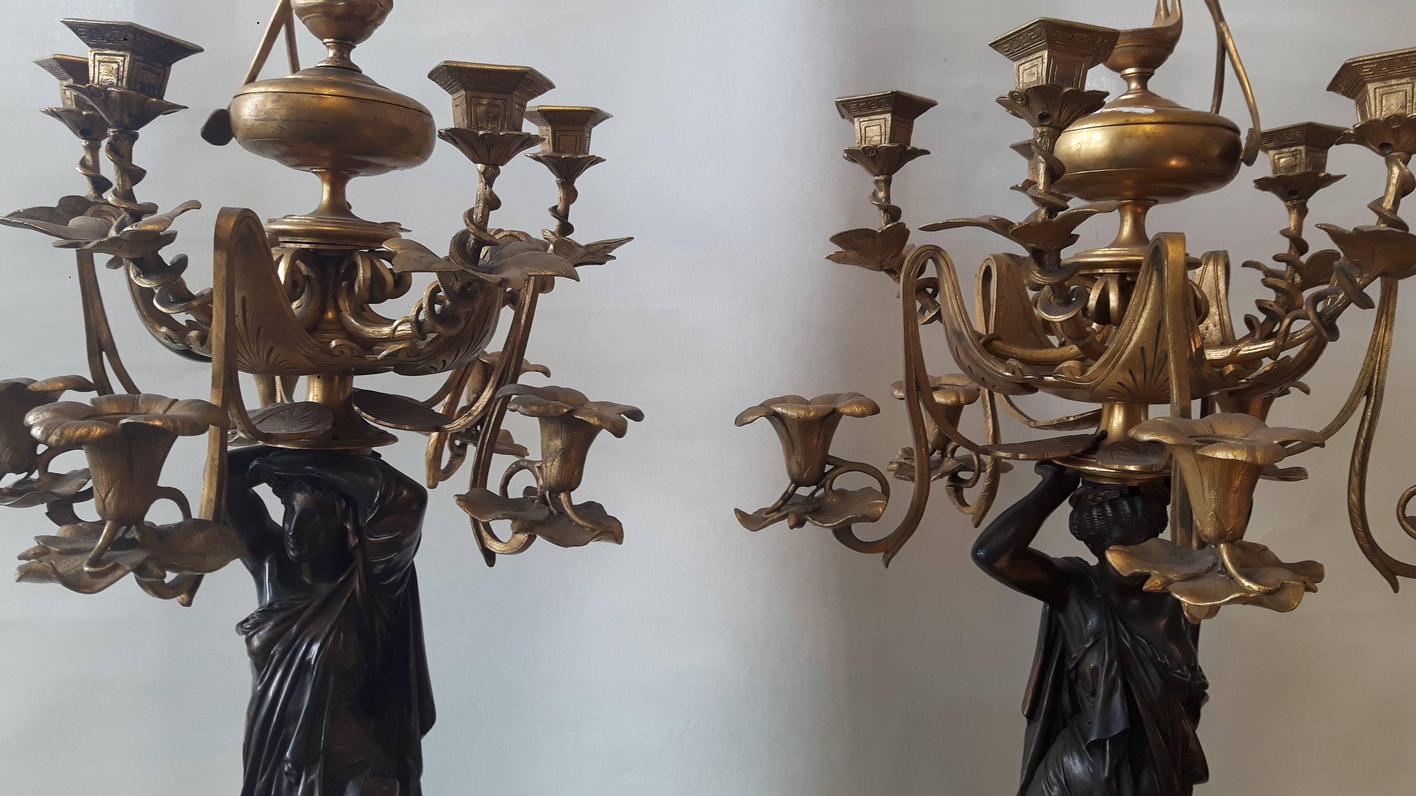 A very large pair of bronze and gilt candelabra in the shape of Grecian water carriers. The figures rest on a tripod shaped base, of which the feet are depicted as lion's feet adorned by eagle’s heads.
