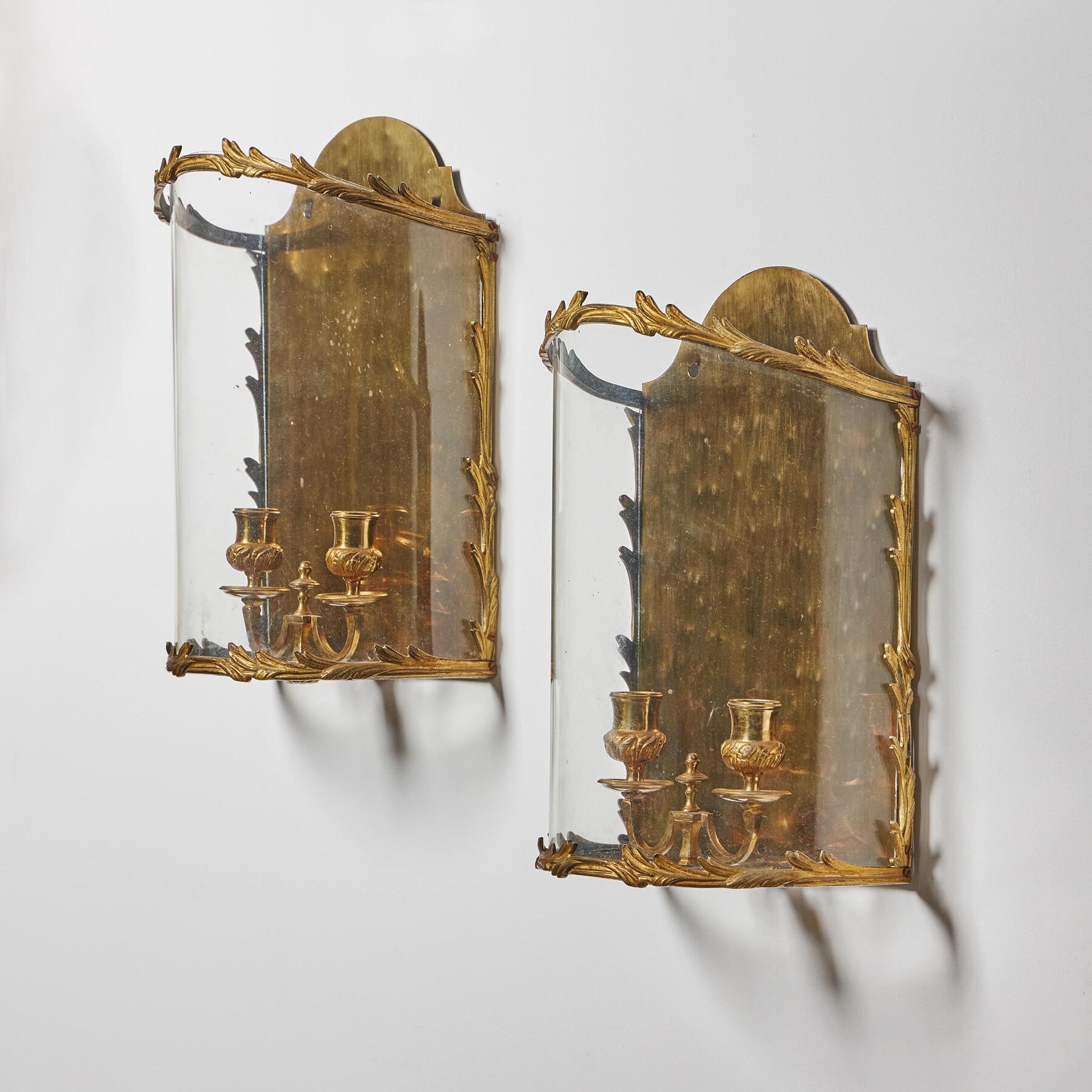 Paire inhabituelle de lanternes murales de style Louis XV du début du 20e siècle en laiton doré avec un front arqué 

Français - Circa 1900

Ces lanternes murales sont dotées de deux bras de bougie finement moulés, fixés à une base en laiton poli et