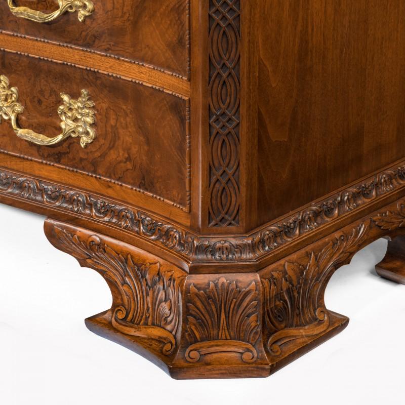 An unusual pair of early 20th century walnut serpentine commodes, each of with two short drawers above a brushing slide and three long drawers, decorated with burr-walnut panels within bead and reel borders, carved with acanthus leaves on the feet