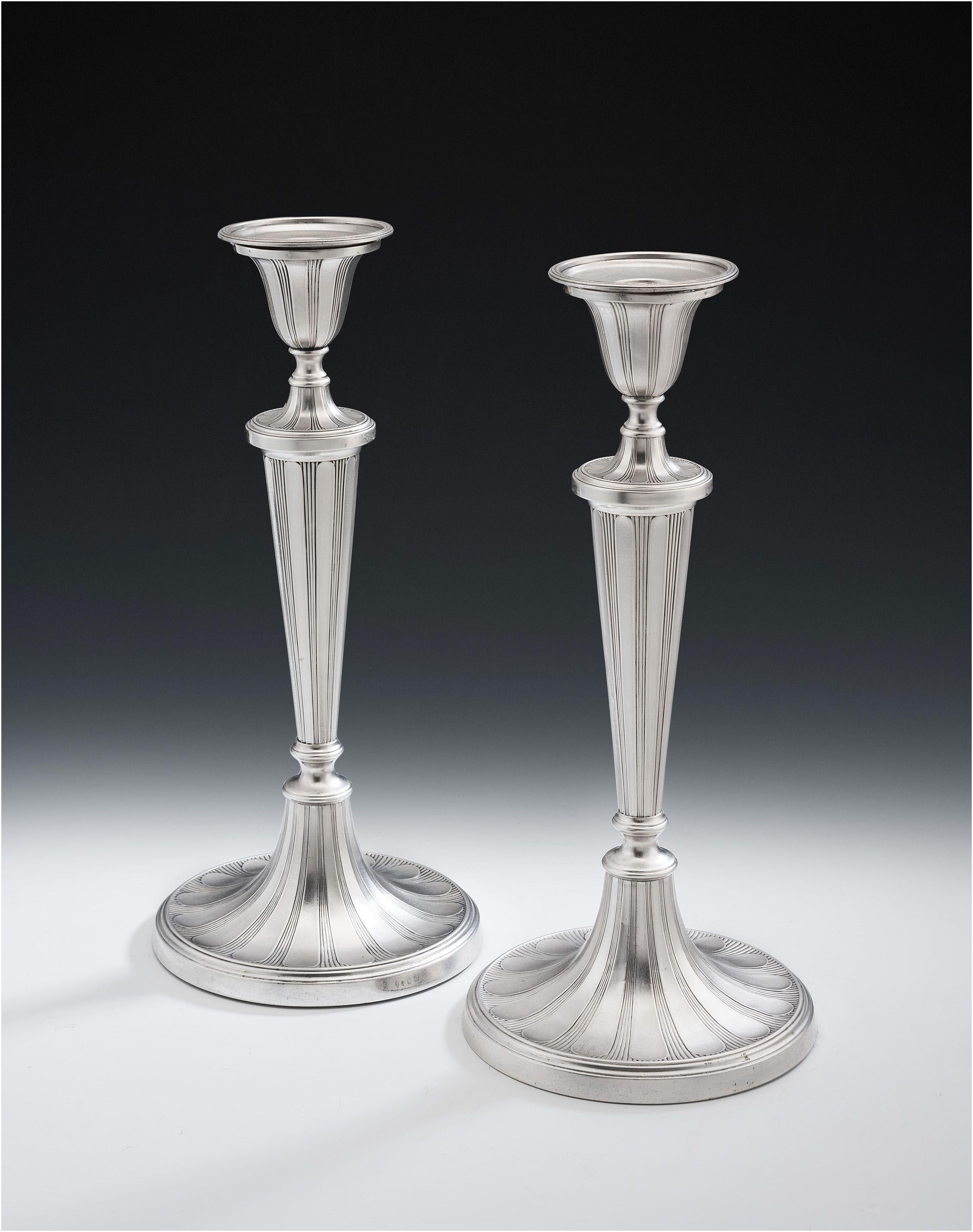 These exceptionally fine and unusual George III sterling silver candlesticks were made in Sheffield in 1790 by Tudor & Leader. The candlesticks are of a large size and stand on circular bases. The bases, tapering stems, and tulip shaped sockets are