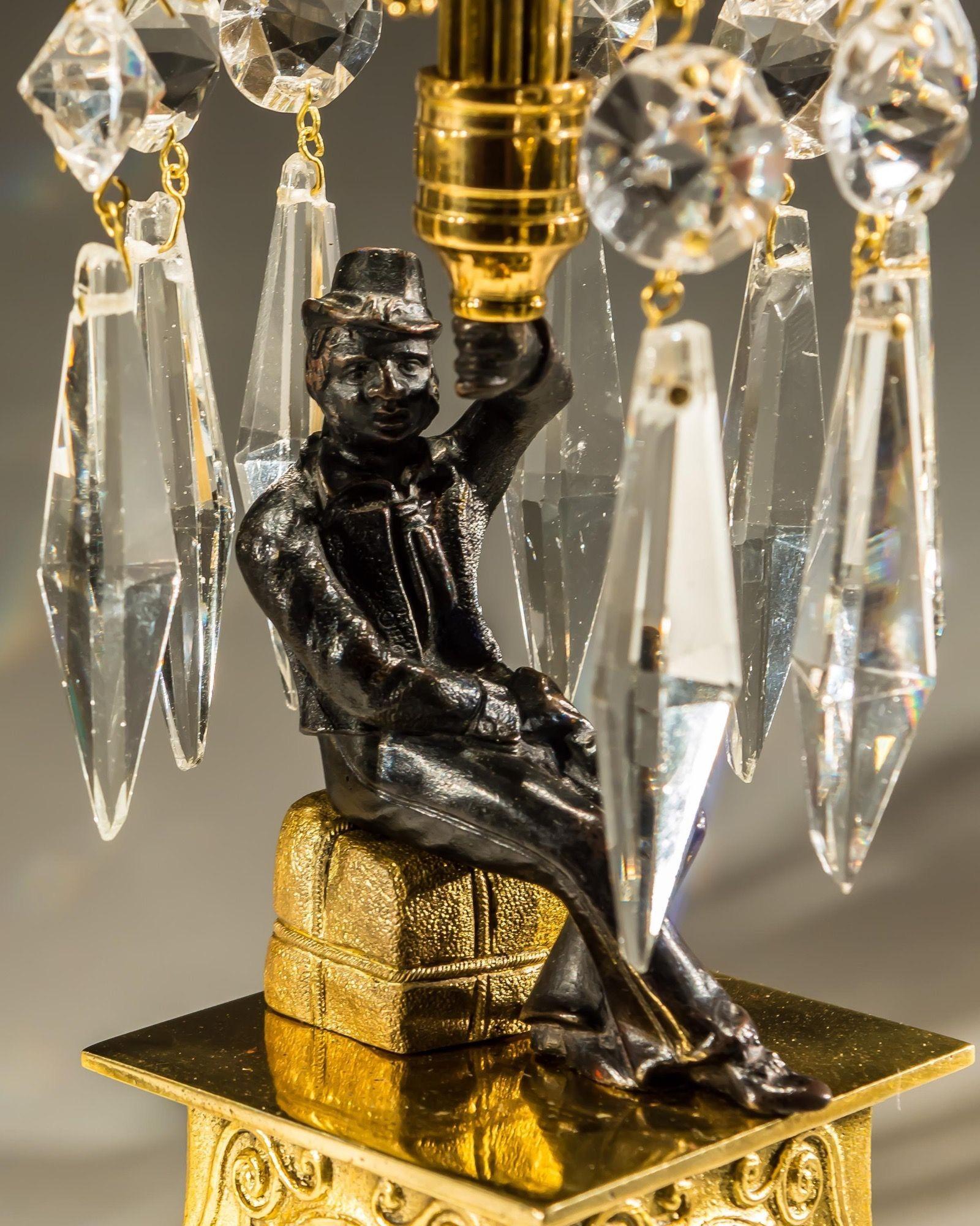 An unusual pair of gilt lacquered and bronzed candlesticks raised on a decorative plinth with seated military figure under an umbrella spray hung with triangularly icicles drop and round spangles