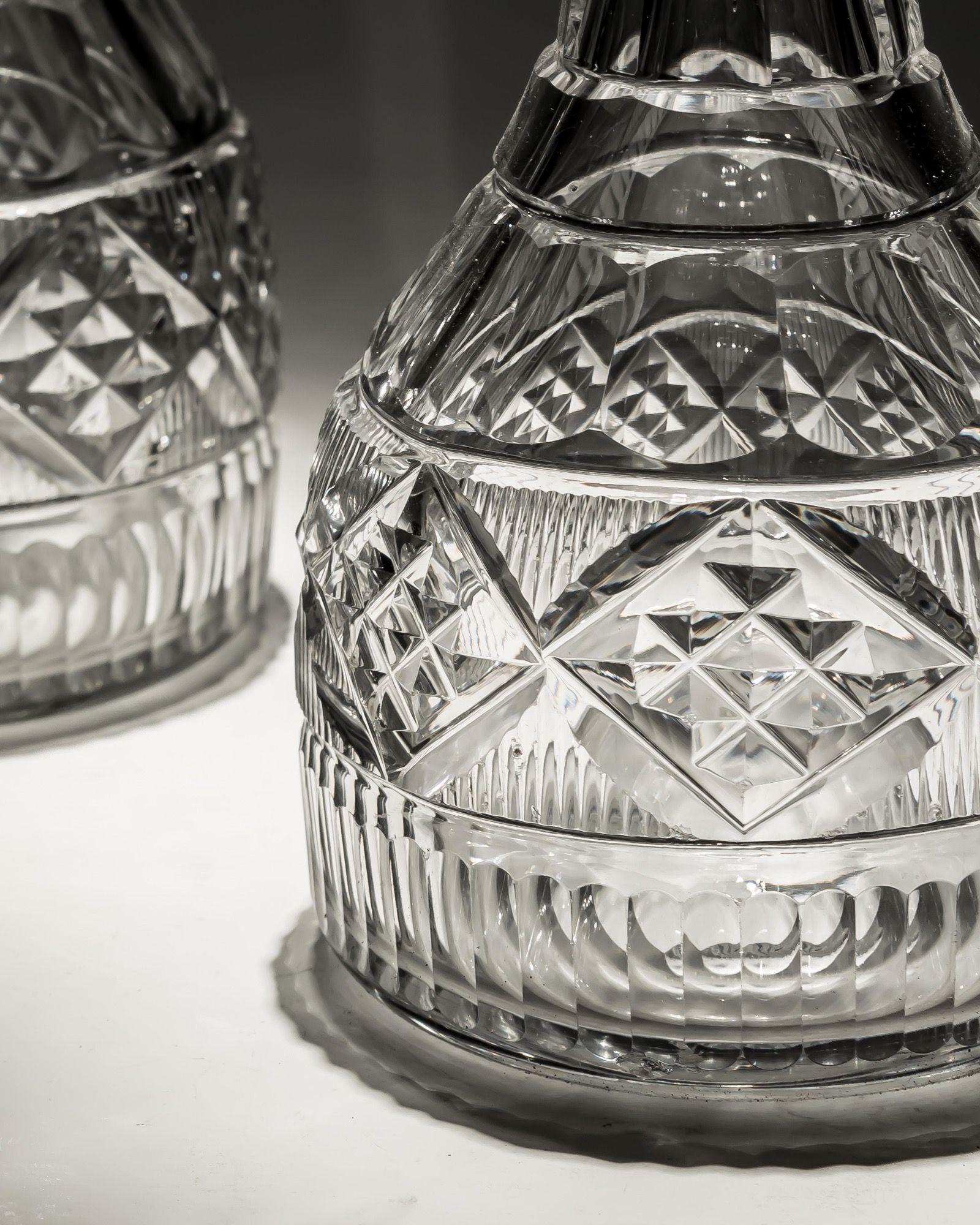 Une paire inhabituelle de carafes irlandaises avec trois anneaux coupés, une bande coupée en tranches, des panneaux coupés en diamants et une base coupée en cannelures.