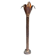 Un lampadaire inhabituel avec un vrai tronc de palmier et des feuilles en bois