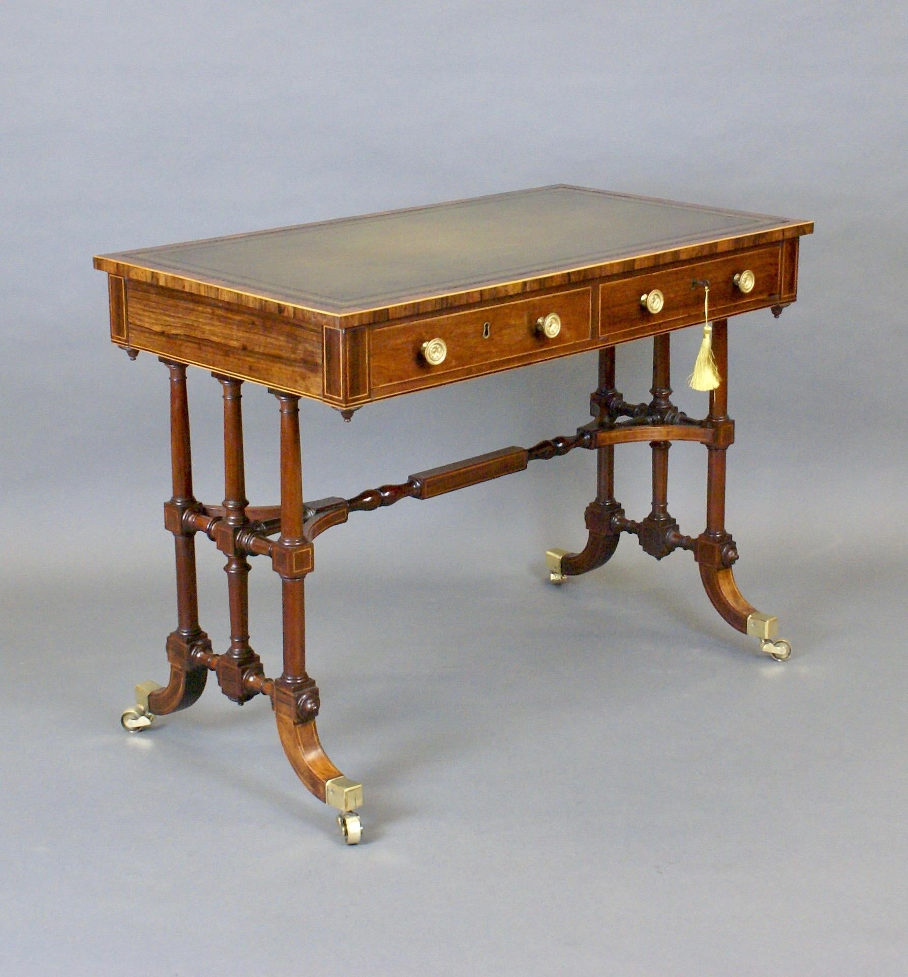 An unusual Regency rosewood writing table. Raised on sabre legs with brass castors and with triple turned supports to either end united by a stretcher. Above are two mahogany lined frieze drawers with dummies on the reverse and a banded top with a