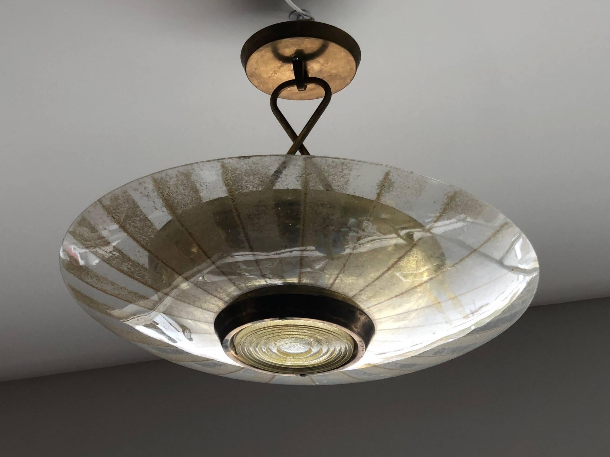 An interesting chandelier by Lightolier, circa 1950s. Perforated brass shade, glass reflector with Fresnel prism. Original canopy. Signed with a green label.
