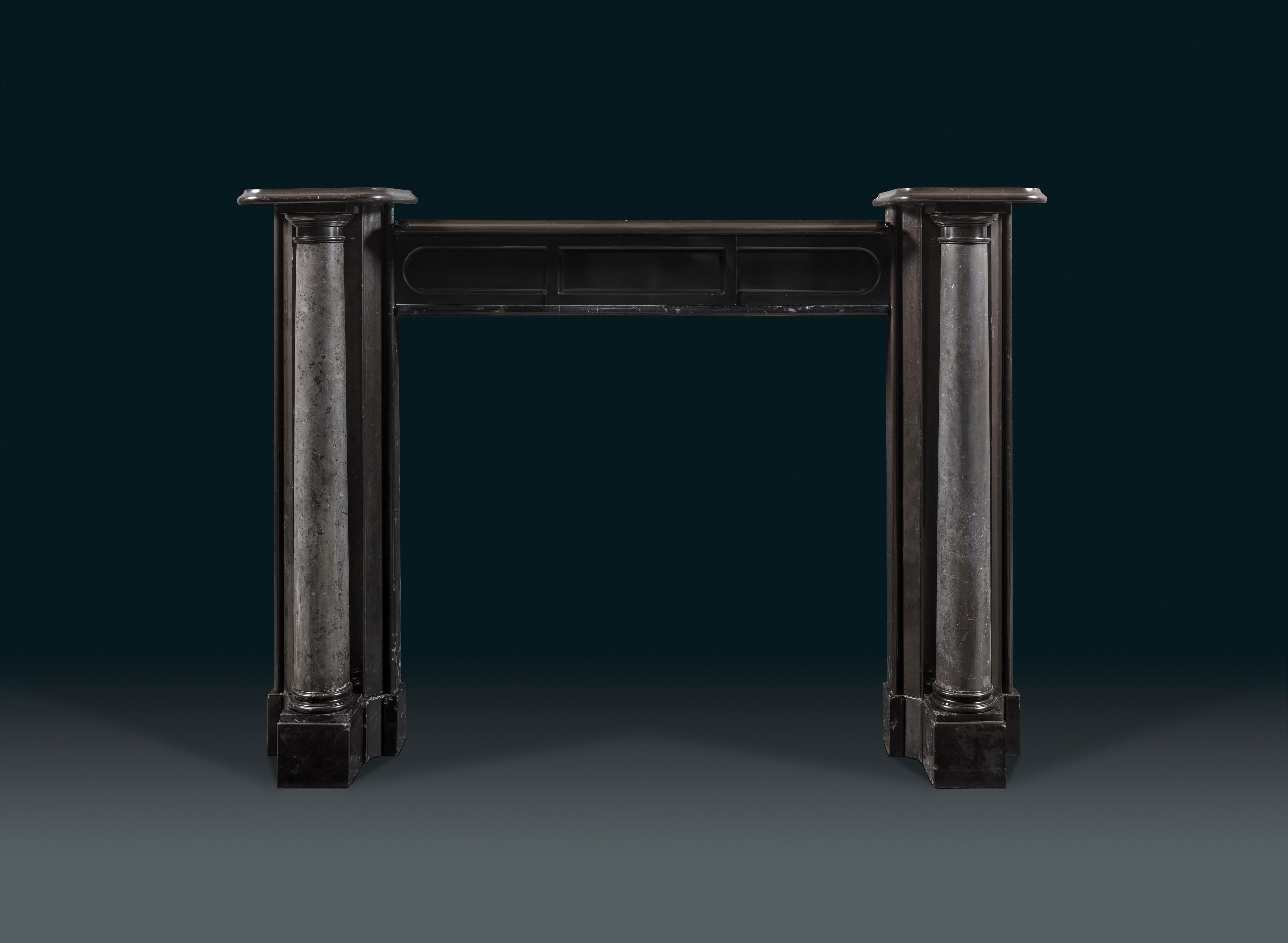 A highly unusual William IV column chimneypiece exhibiting fine European black marbles.
The body of this 19th century fireplace is carved from solid Belgium Black finished in a high polish, punctuated by tapering Doric columns that are unpolished,