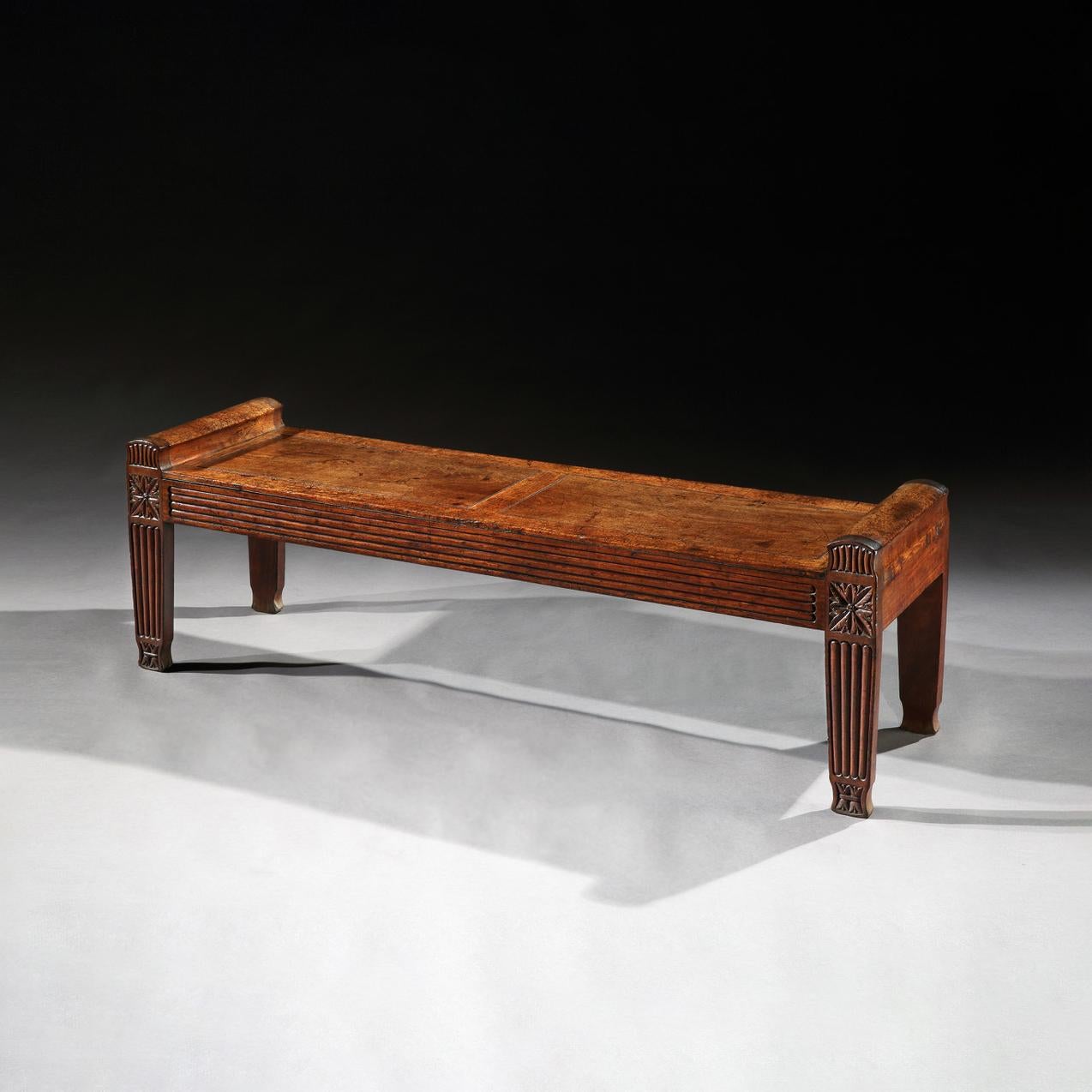 In the manner of Charles Heathcote Tatham.

This window seat, elegantly framed and panelled with a reeded frieze, rests upon reeded legs adorned with finely carved paterae. Its impressive size, nearly five and a half feet long sets it apart, and its