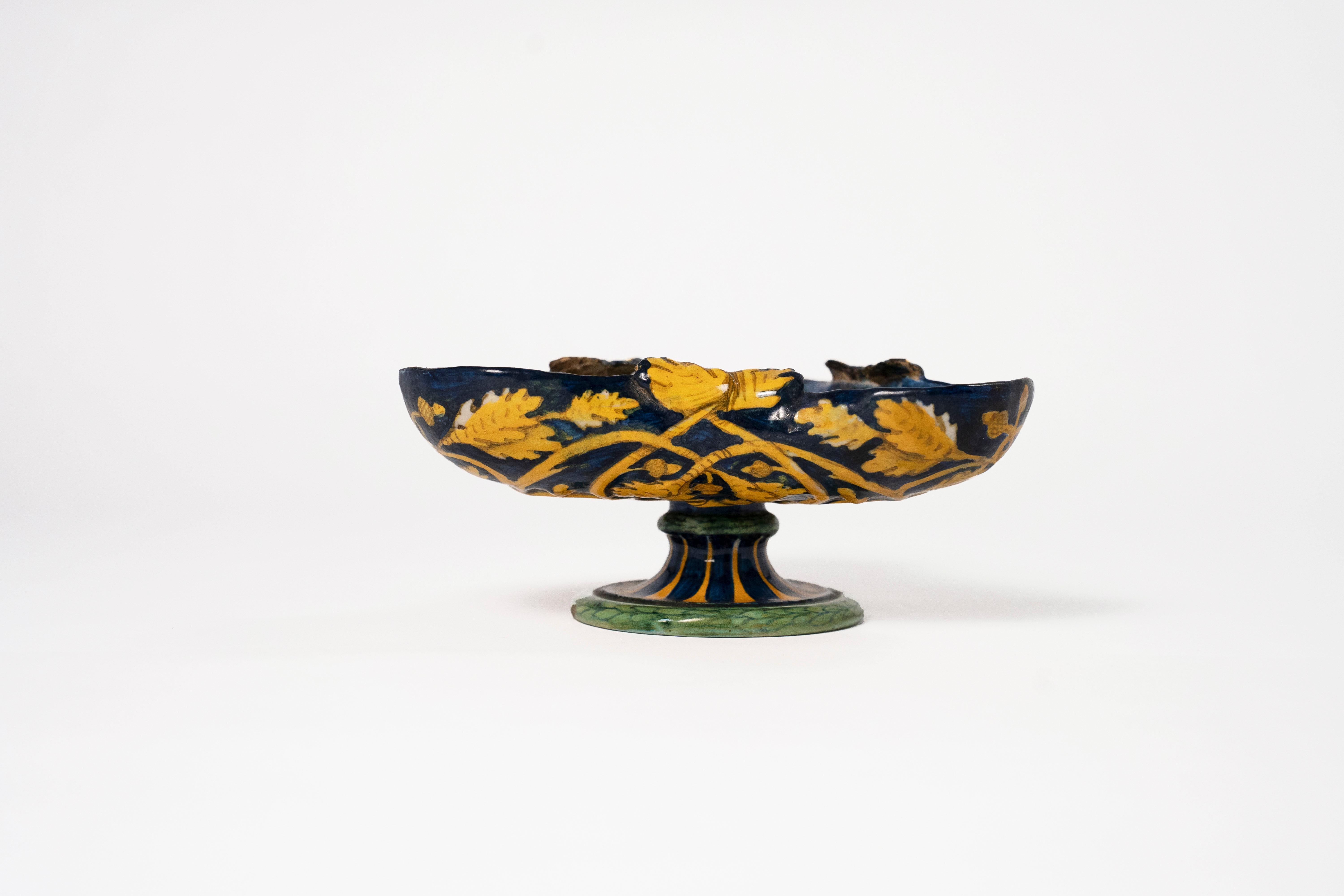 An Urbino Maiolica Istoriato Small Tri-Lobed Dish, C1540-1545, Italy.  The blue ground exterior molded with a cerquate design of interwoven oak branches with foliage and acorns.  The interior painted with the story of Apollo & Daphne.  

*The