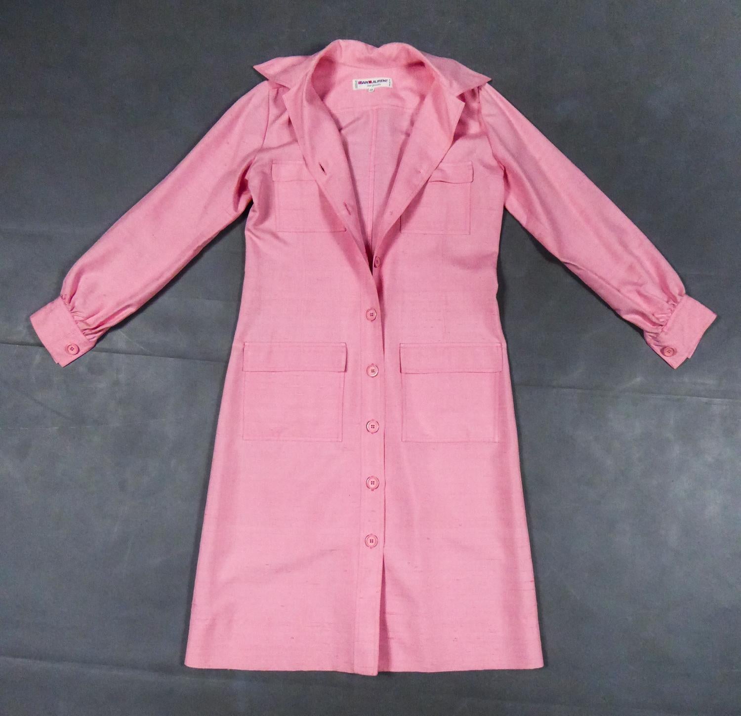 Circa 1980
France

Blouse dress in pink wild silk by Yves Saint Laurent in the spirit of 1970s Saharian style collections. Tubular line slightly flared from the bottom of the skirt. Long sleeves, Italian collar and large pockets with topstitch on