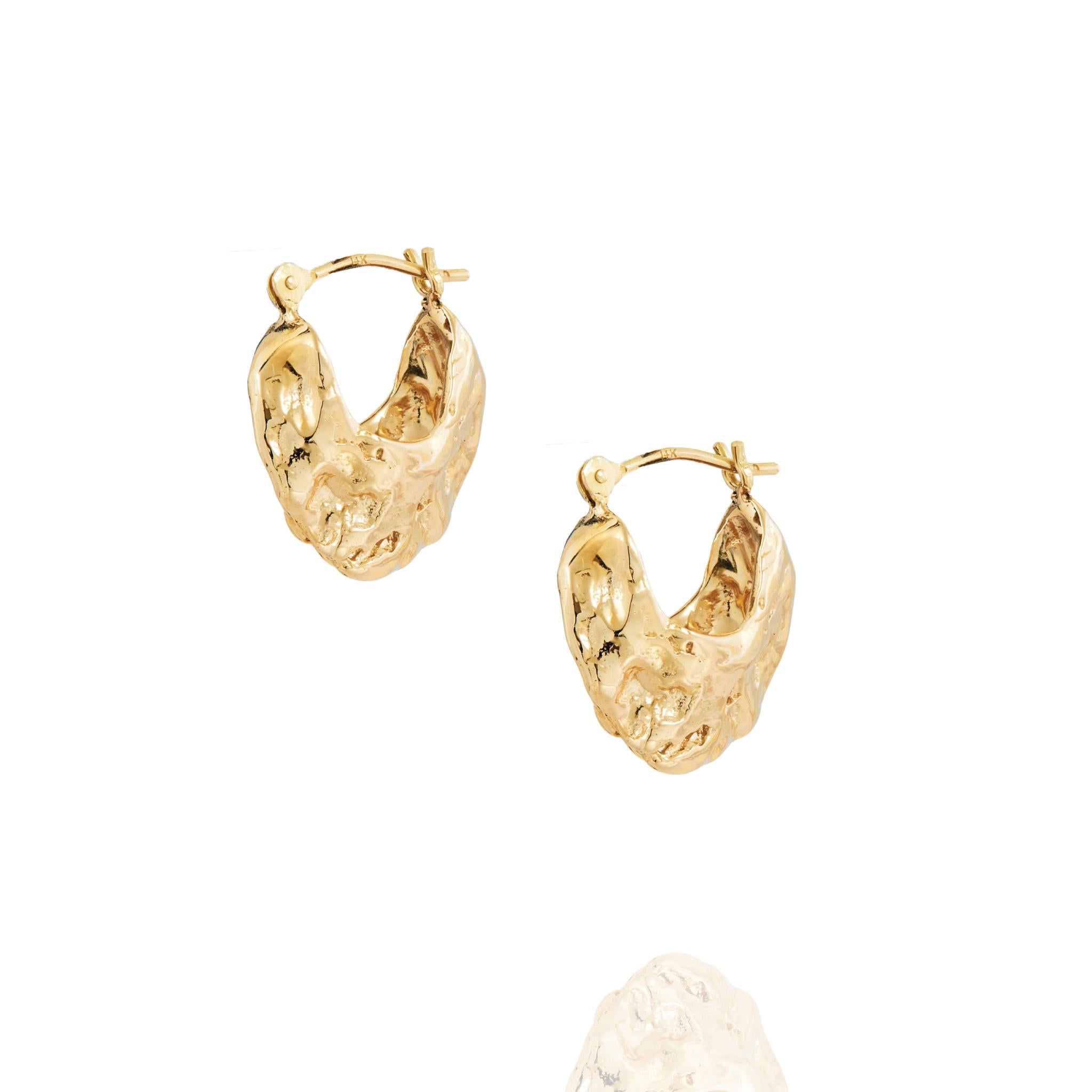 Les boucles d'oreilles Huggie d'Ana Maria sont en or massif 14k.  Pour ce design original, nous nous sommes inspirés du surréalisme, en explorant le concept d'espace négatif.  Influencés par les différentes formes de coquillages trouvées, nous avons
