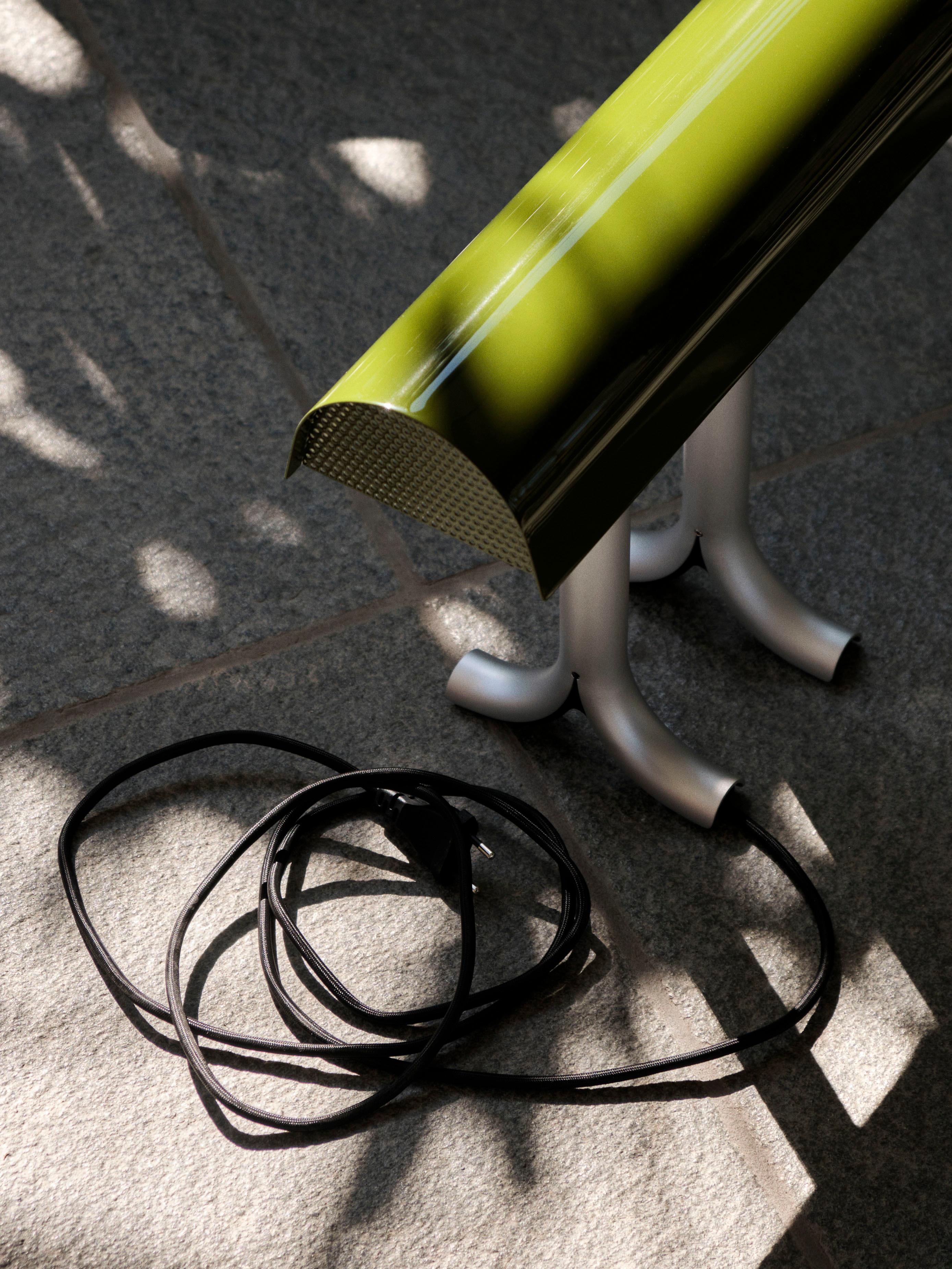 Sam Weller's Anagram Table Lamp fuses functionality with visual appeal to create a table lamp with a robust construction and strong personality. 
Featuring a generously curved, glossy shade that sits atop two split anodized aluminum legs, the