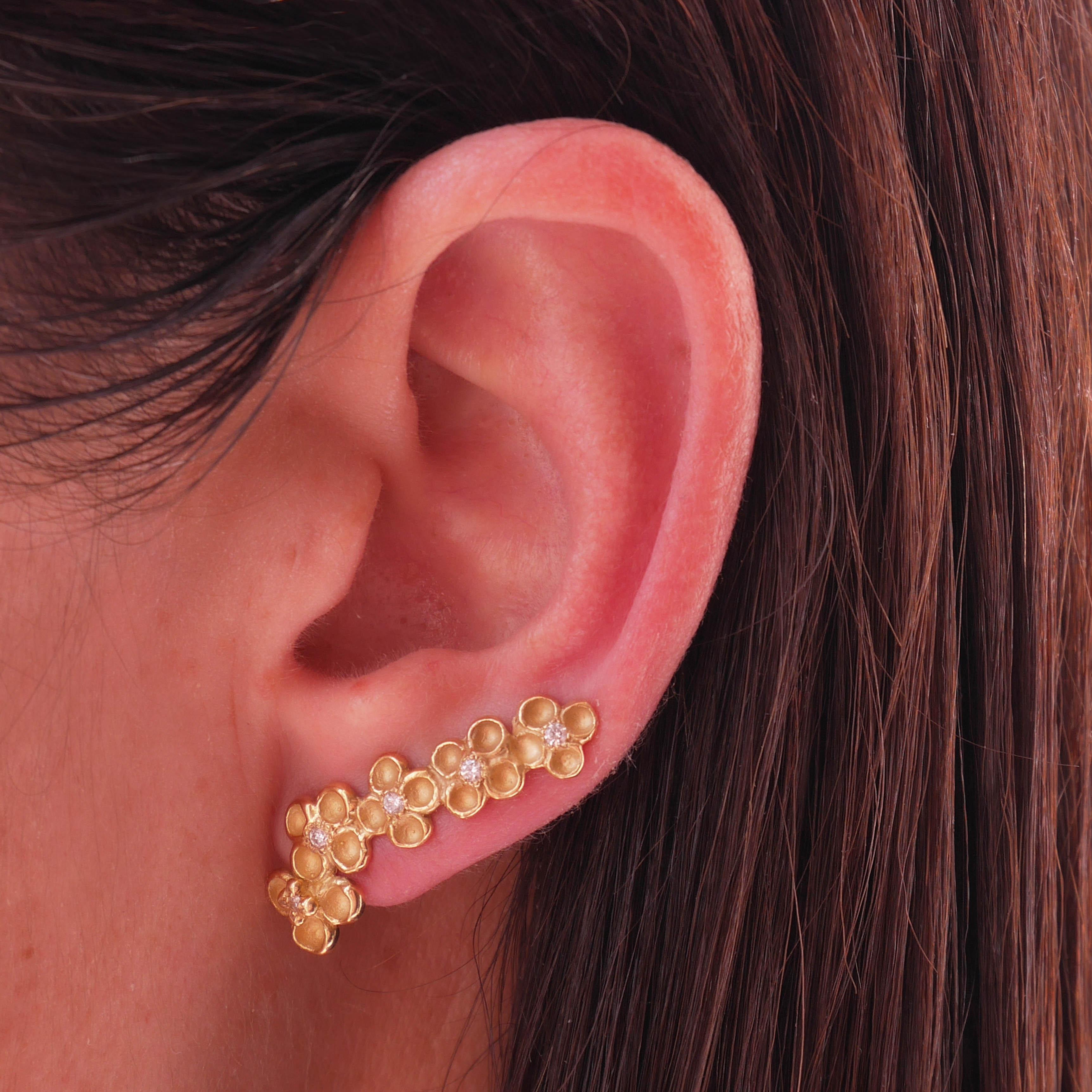 Clusters of contrasting sculpted flowers make up these one-of-a-kind ear climbers creating the illusion of multiple piercings. Perfectly crafted to follow the curve along with the cartilage, they are made in 18 Karat yellow gold app. 5grm. They are