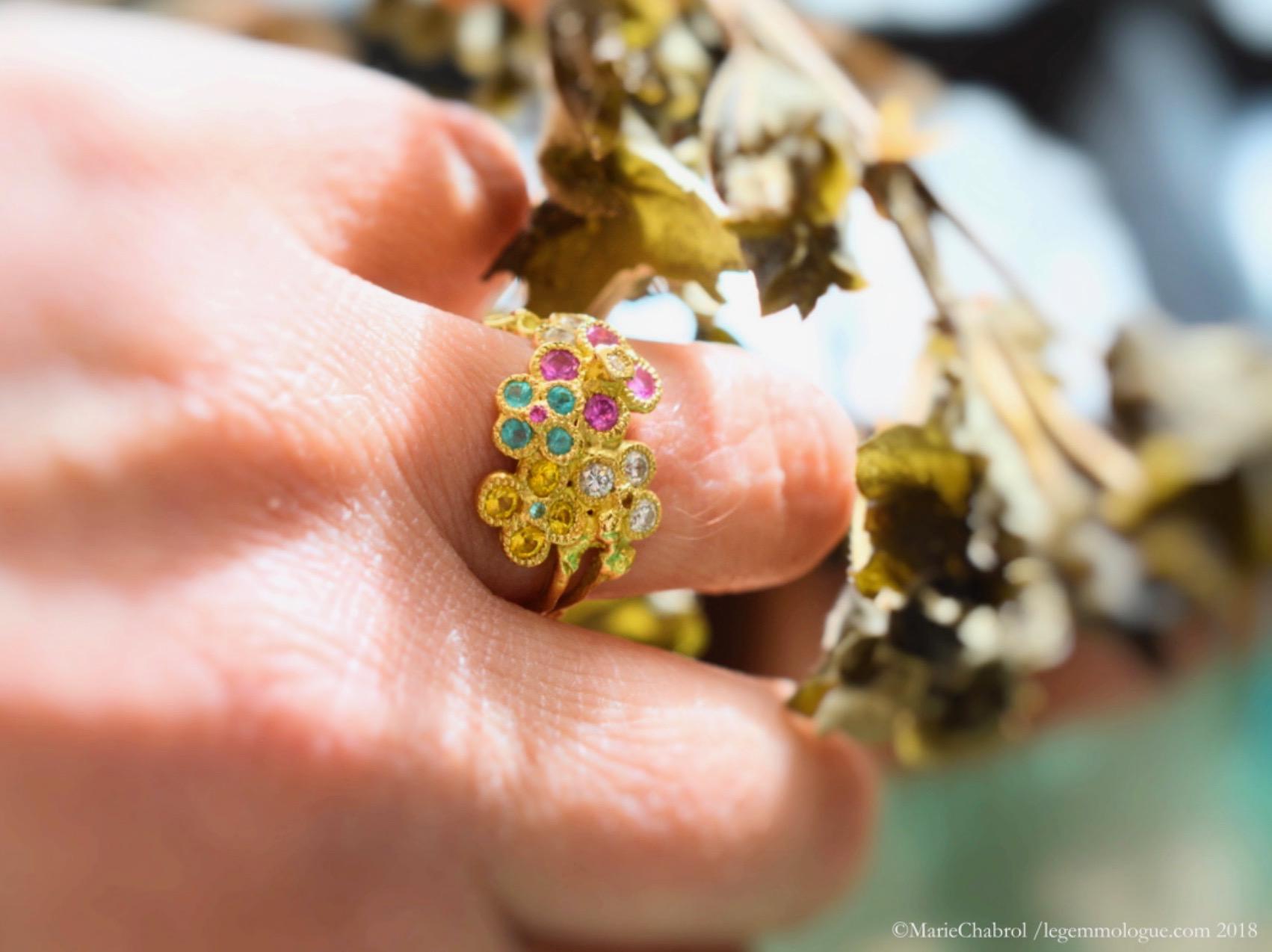 This ring is handmade in 18K yellow gold. Chiseled flowers with a matt and shiny polish. It is set with diamonds of approximately 0.17 carat, yellow sapphires 0.31 ct approx. Tourmaline Paraiba 0.9 carat approx. and pink sapphires 0.19 carat approx.