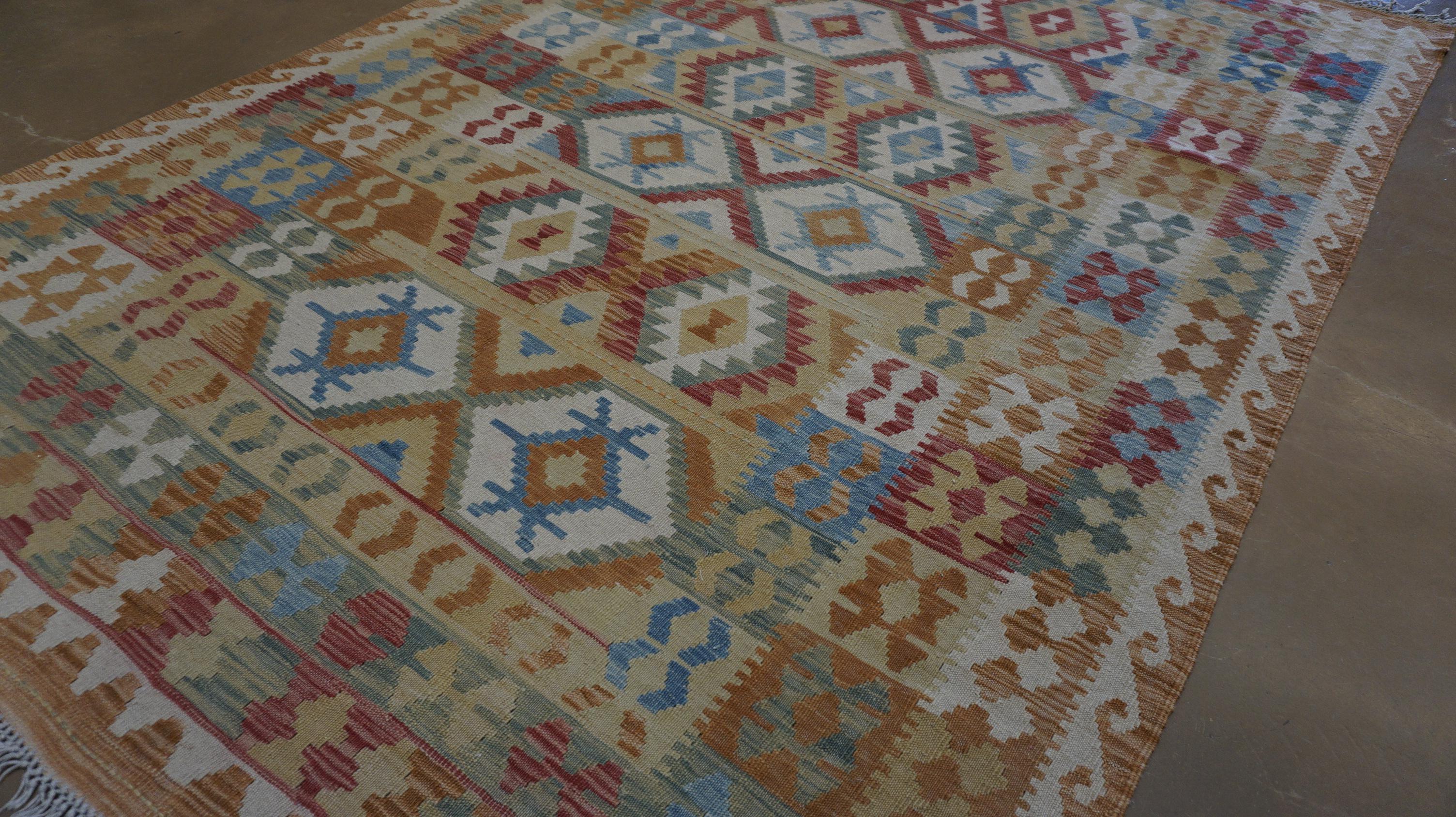 Ce kilim en laine vibrante tissé à la main est une belle célébration de la géométrie tribale et des teintures naturelles audacieuses. Réalisé selon les techniques traditionnelles de tissage à plat par des artisans qualifiés, ce tapis présente une