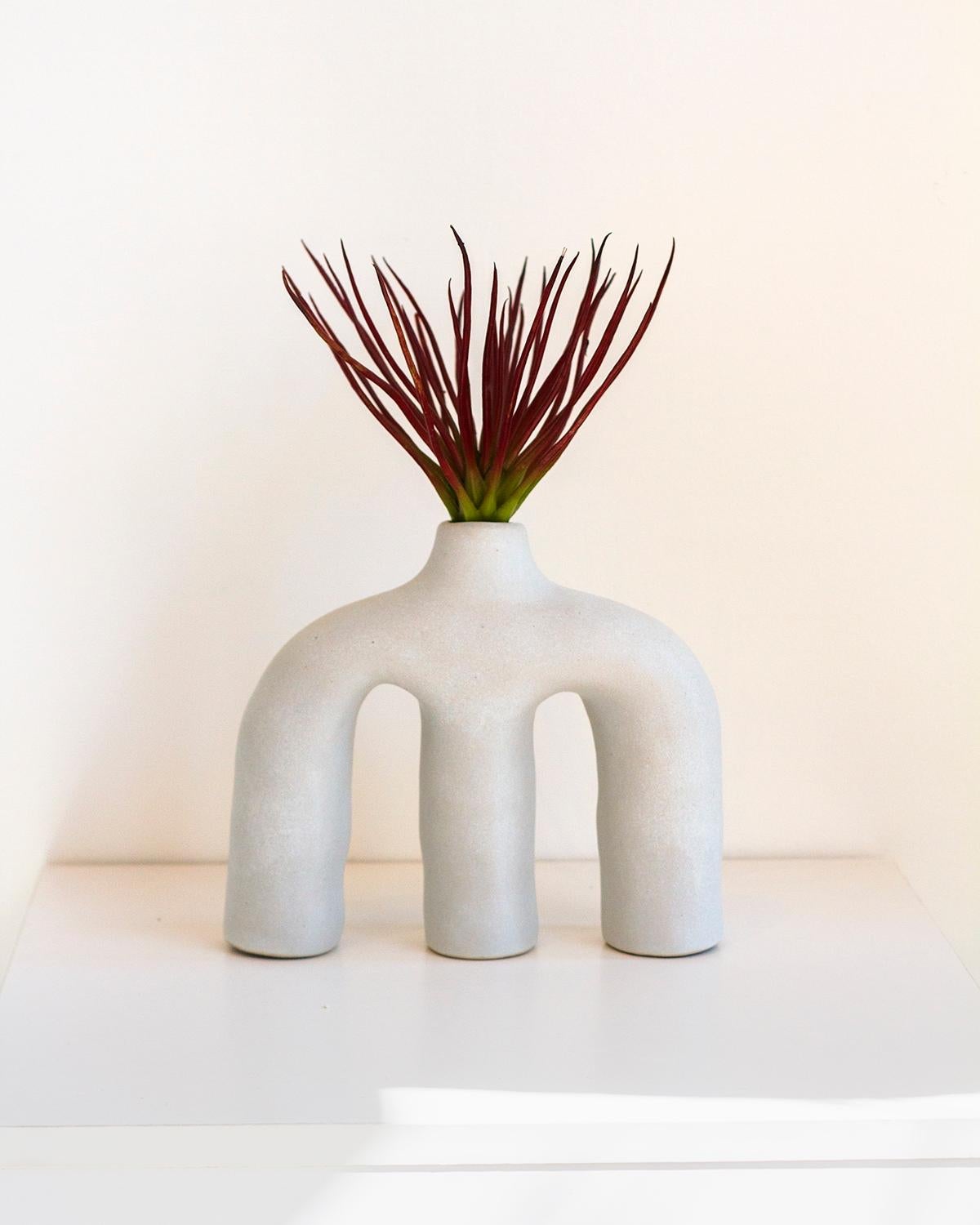 Ce vase en terre cuite d'une beauté unique possède trois pieds et une petite ouverture dans le haut pour les fleurs ou les branches. Il a été fabriqué à la main dans un style moderne organique pour s'intégrer dans n'importe quelle maison