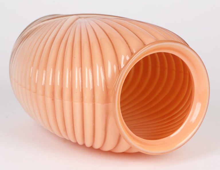 A stylish North American art deco style molded fan design salmon pink vase by Anchor Hocking and dating from around 1980. The vase has a molded ribbed patterning with three interloping fan shaped designs. The vase is made in clear glass with a