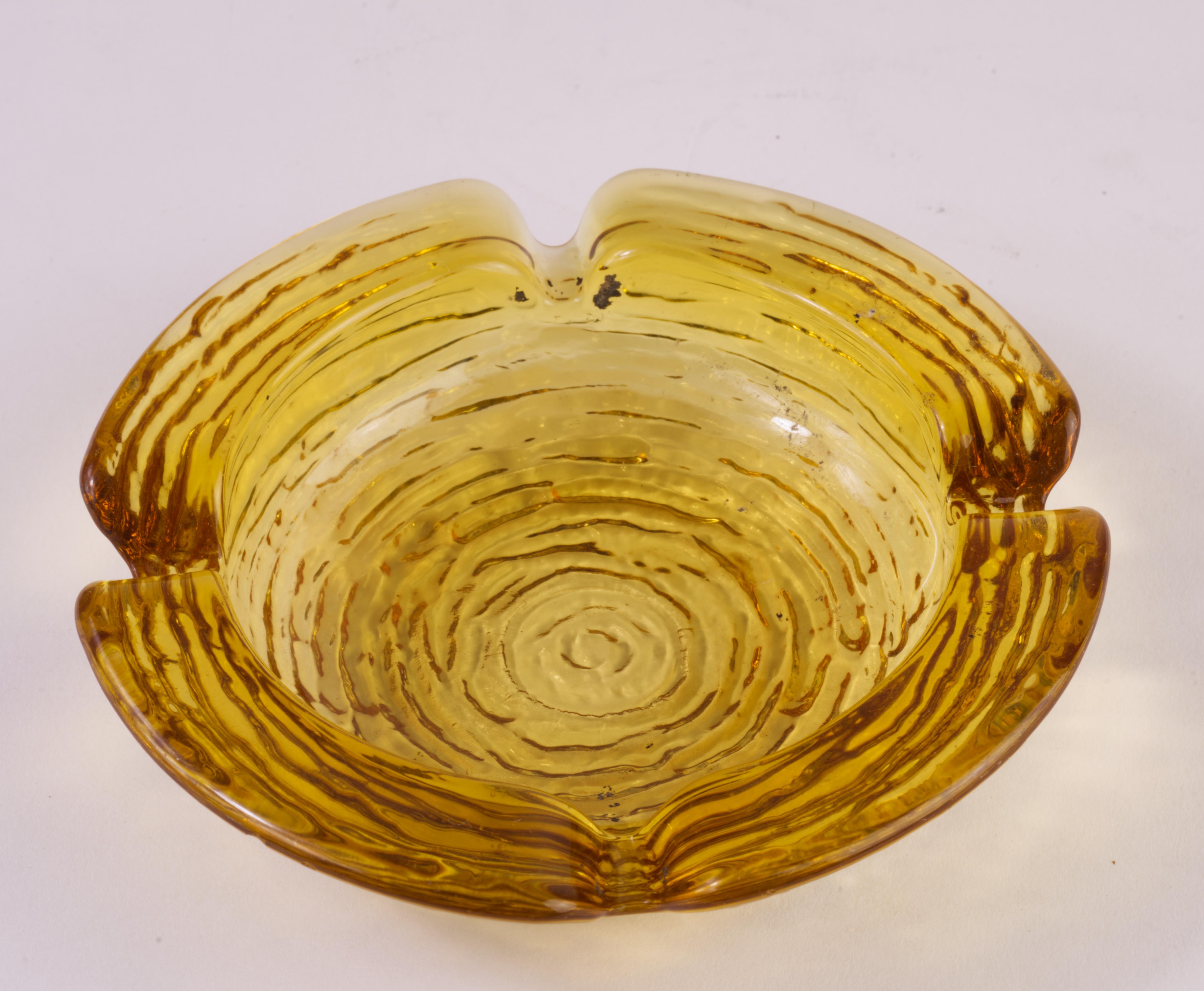  Le cendrier en verre doré texturé a été fabriqué par Anchor Hocking dans le cadre de la série Soreno. Les cendriers Soreno, également appelés Calle, présentent un motif composé d'une série de lignes en relief formant un motif presque labyrinthique
