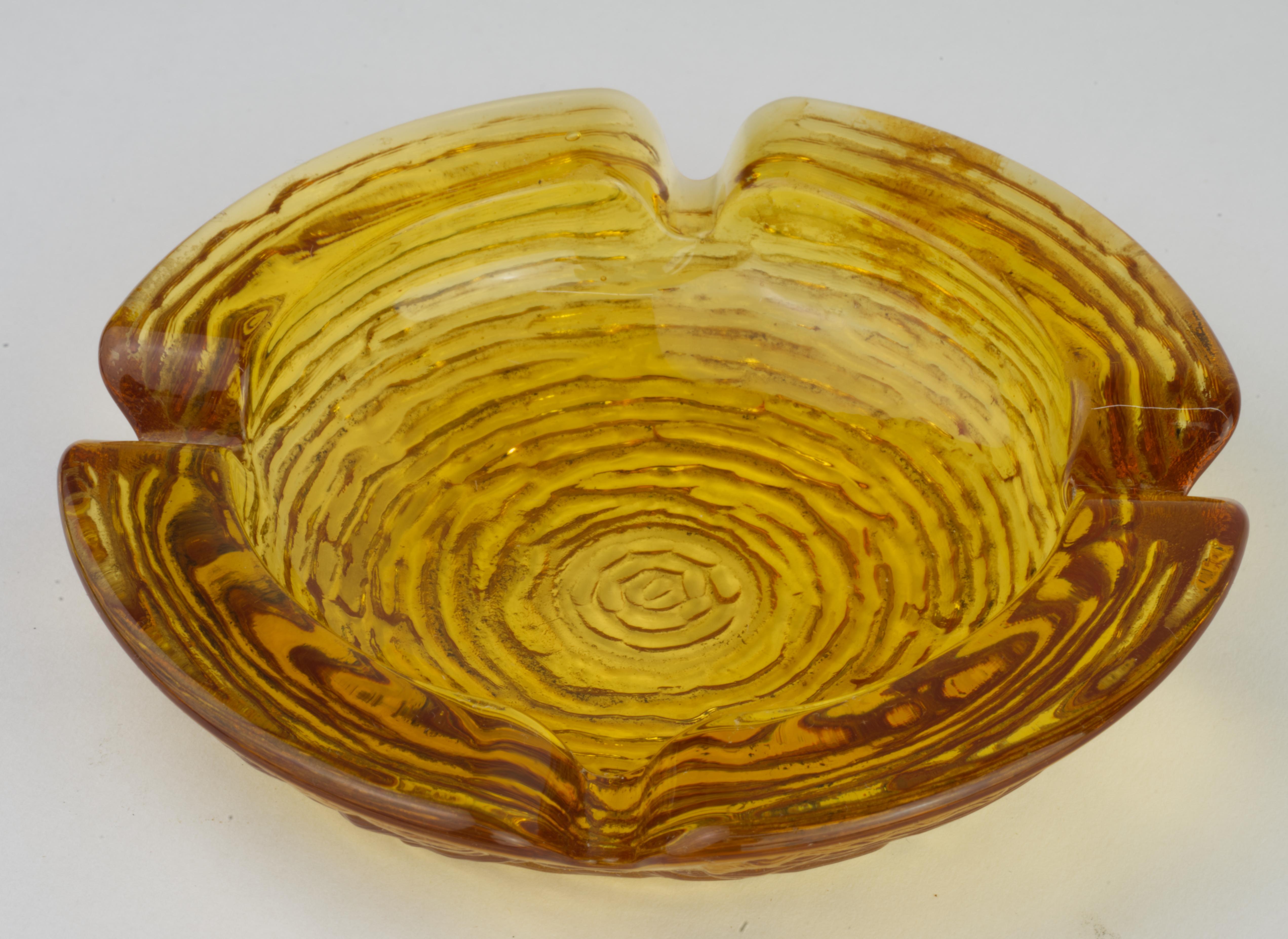  Textured amber glass ashtray was made by Anchor Hocking as a part of Soreno series. Soreno ashtrays, also called Lido, have a pattern of a series of raised lines forming an almost maze-like pattern on the exterior of each piece. 

This is a smaller