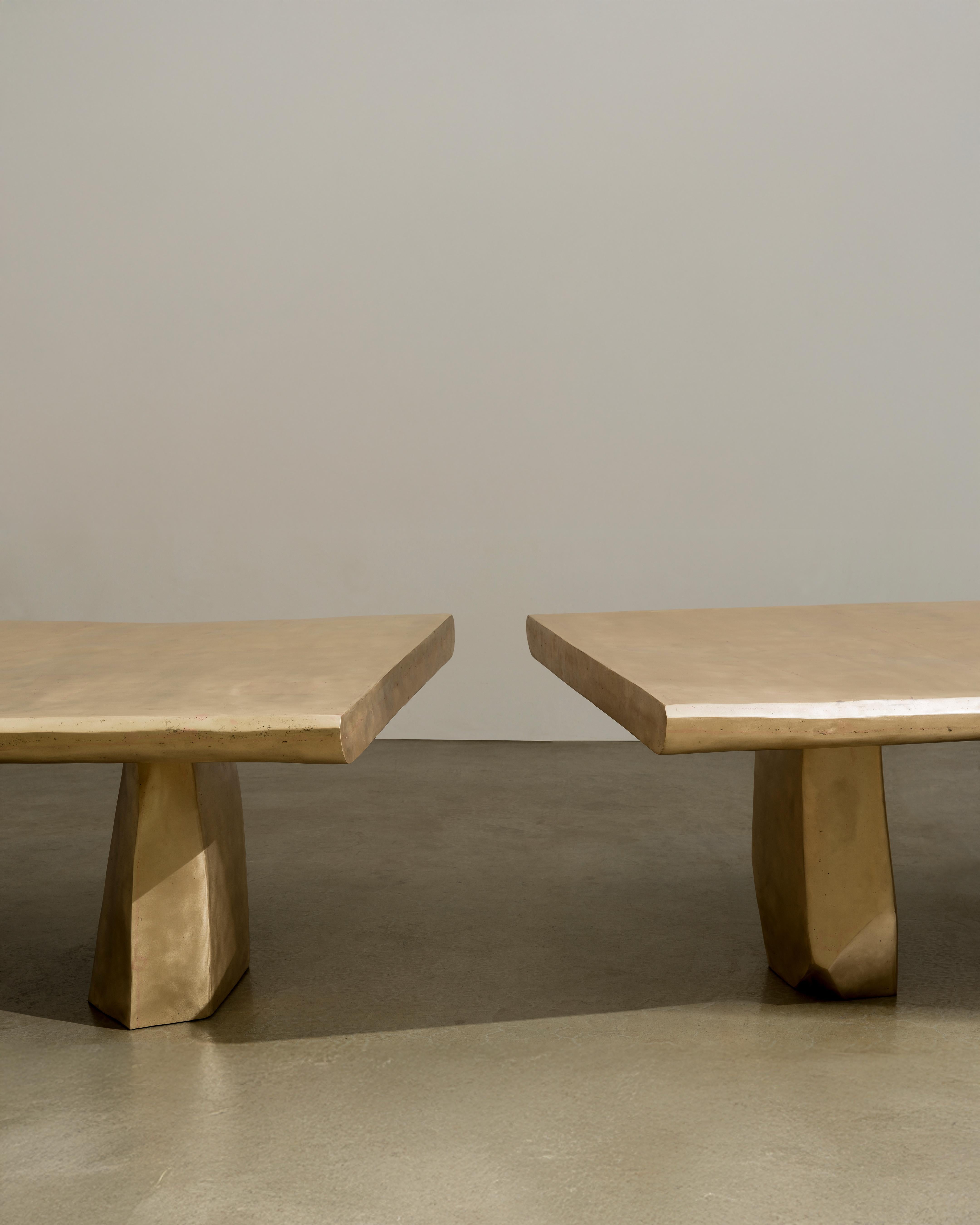 Anchored Void is a modular bronze dining table with a split tabletop configuration. The design consists of two independent sections, one longer and one shorter, that can be arranged together as a single composition or displayed separately. This