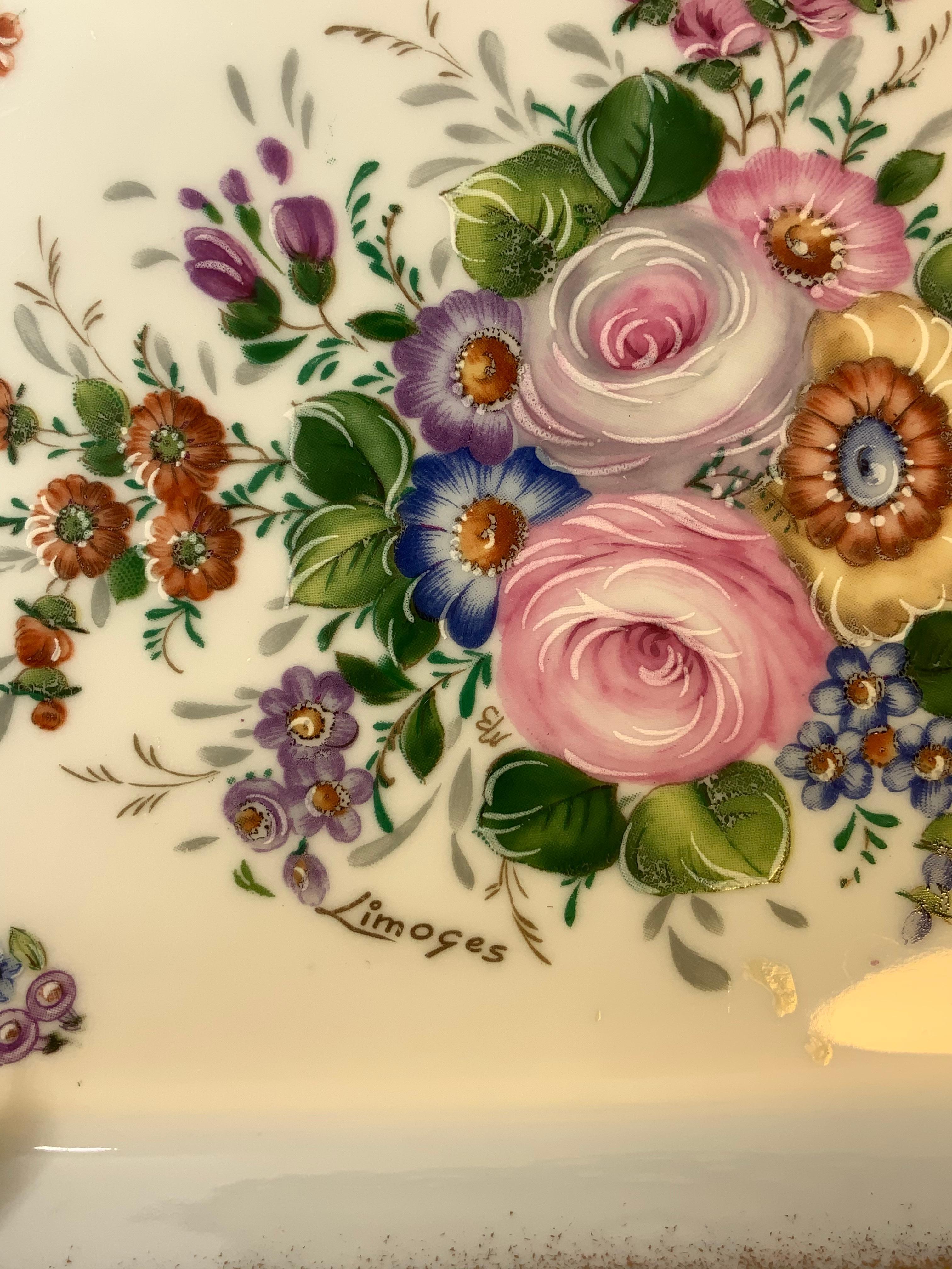 An octagonal bronze mounted porcelain dresser tray. It is hand painted with a bouquet of flowers & foliage in its center against a white background. The gilded borderline of the tray is framed by a patinated bronze border decorated with a ribbon