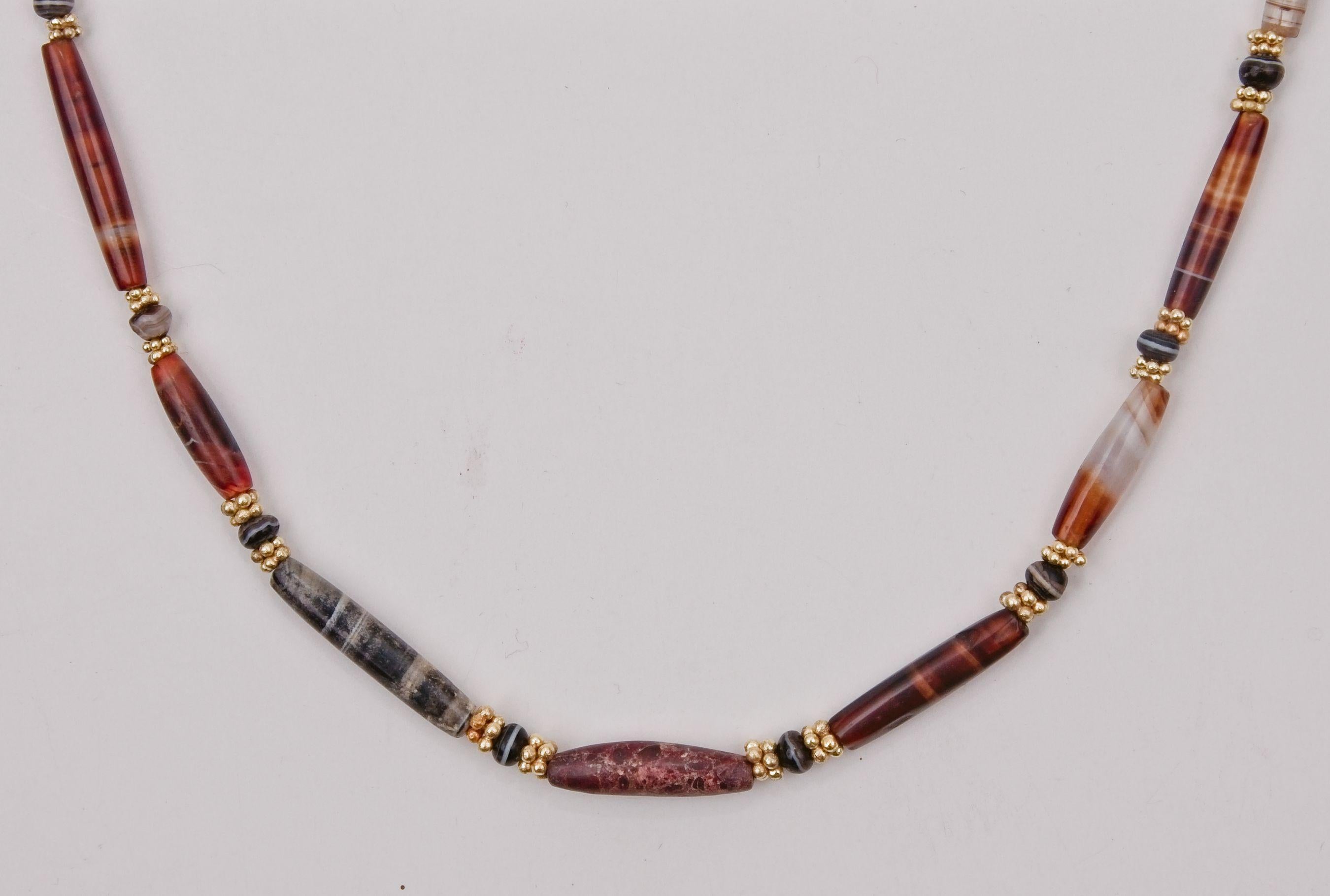 Fifty-one agate beads alternating with pairs of 22k gold granulated ring spacer beads. Twenty-five of the agate beads are long tapered barrel-shaped beads and twenty-six are small spherical, slightly oblate black beads with a white band. The