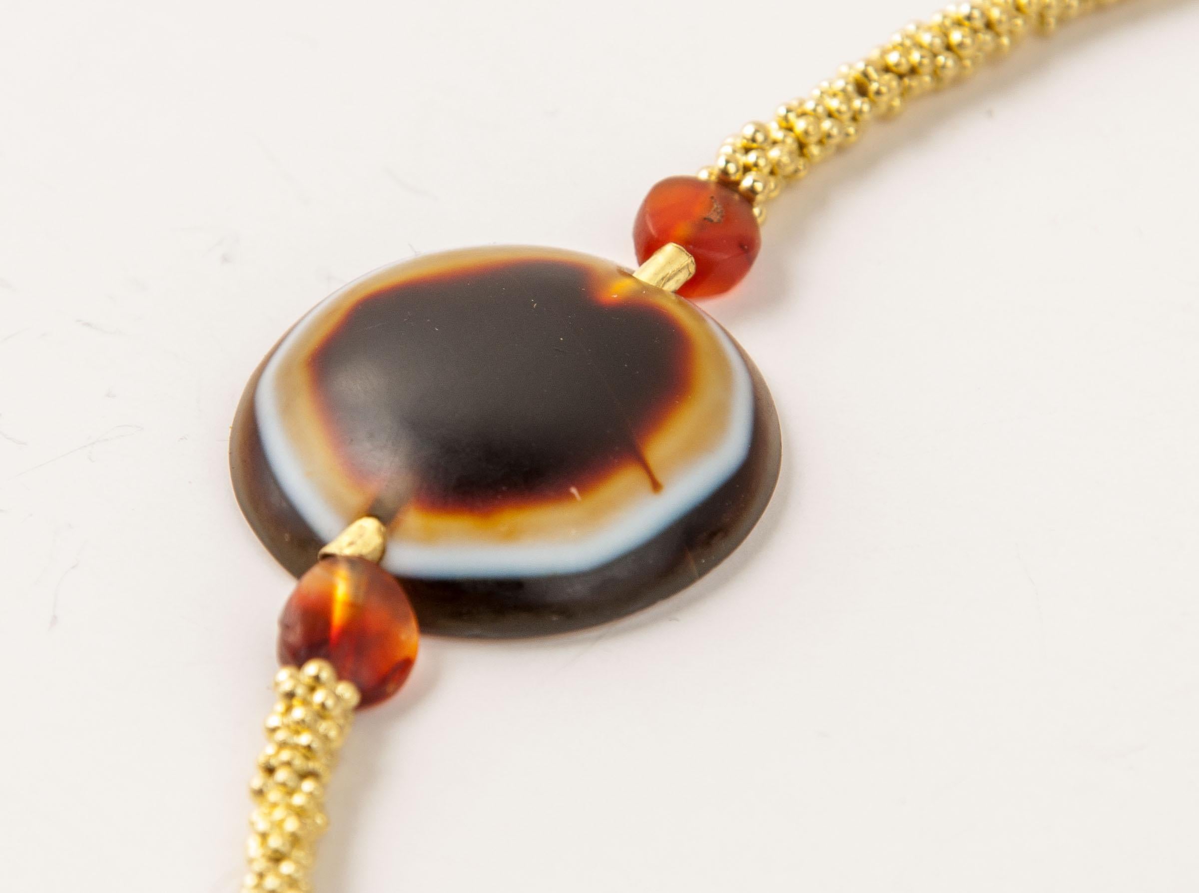 Two hundred fifty six-ball granulated ring spacers, four tabular carnelian beads and a tabular agate ”eye” bead. The eye bead is 2.3 cm in diameter and 5.9 mm in thickness. The diameter of the drill hole is 2 mm. The bead is slightly domed on the