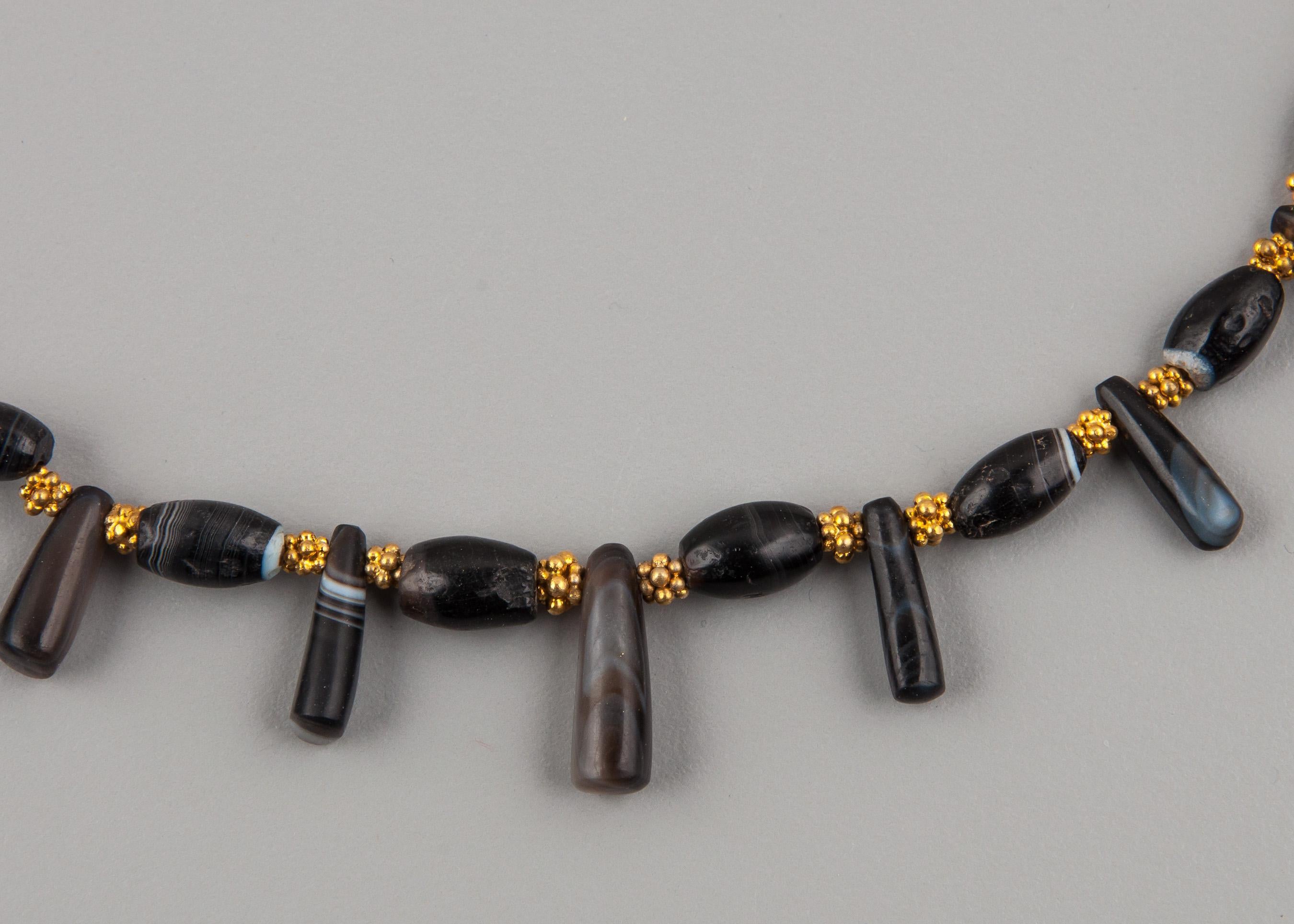 Thirty agate barrel beads and twenty-seven agate pendant beads alternating with vermeil (gilt silver) granulated beads. The barrel beads and pendants graduate in size from the front to the back of the necklace. The largest barrel beads are 1 cm in