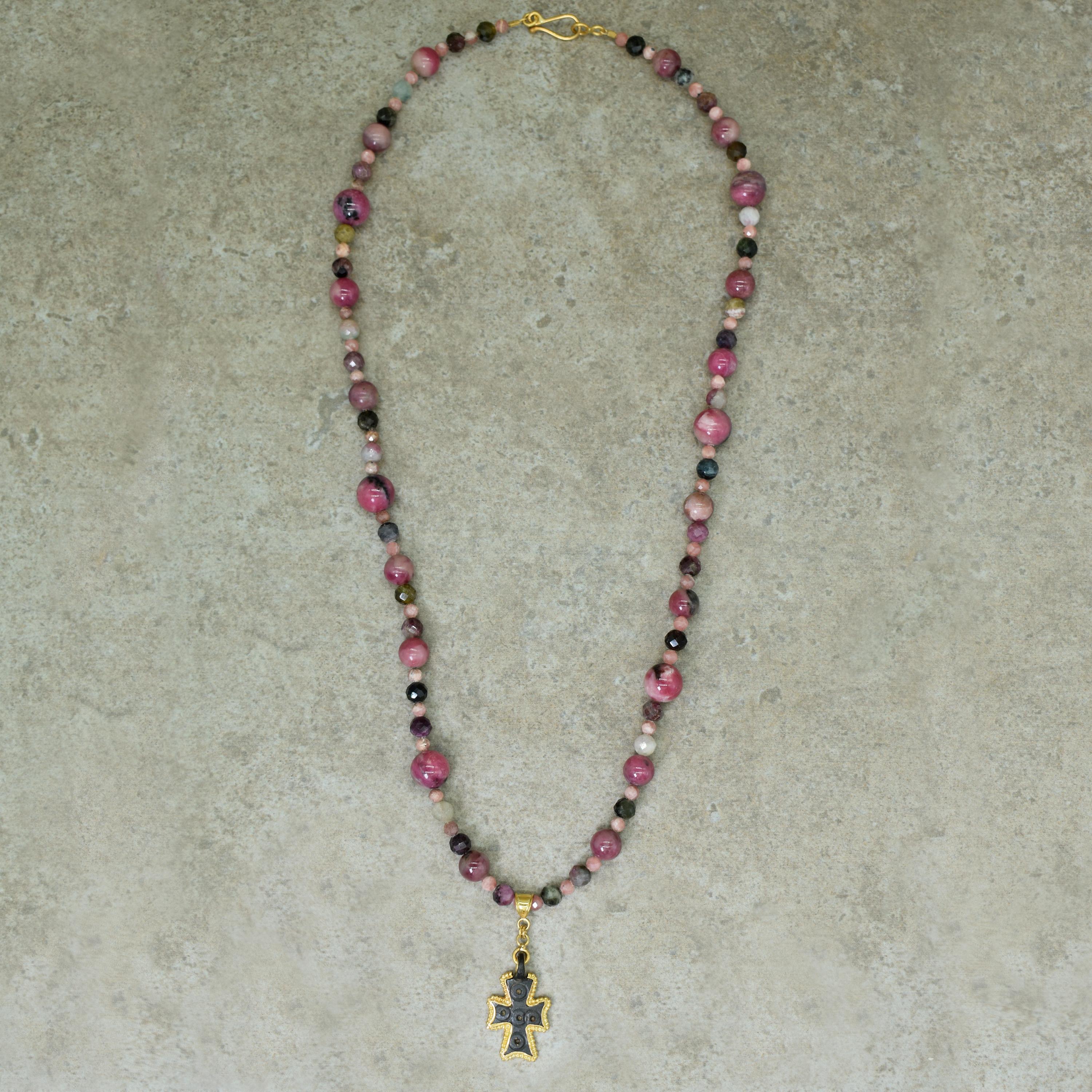 Ancient Byzantine bronze cross pendant contemporarily set with 22k yellow gold on a pink tone beaded necklace featuring Rhodonite, multi-color Tourmaline and Rhodochrosite beads. Beaded necklace is 22.5 inches in length, and is finished with a 22k