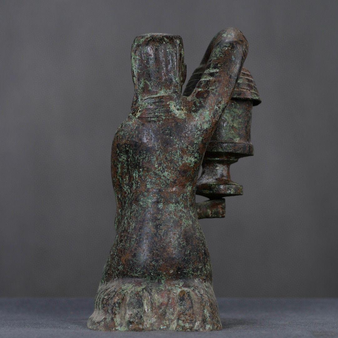 This Vintage Bronze Statue depicts a kneeling human figure, gracefully holding a lantern with both hands, evoking a sense of serenity and reverence. The intricate details of the human form, captured in bronze, showcase the craftsmanship and