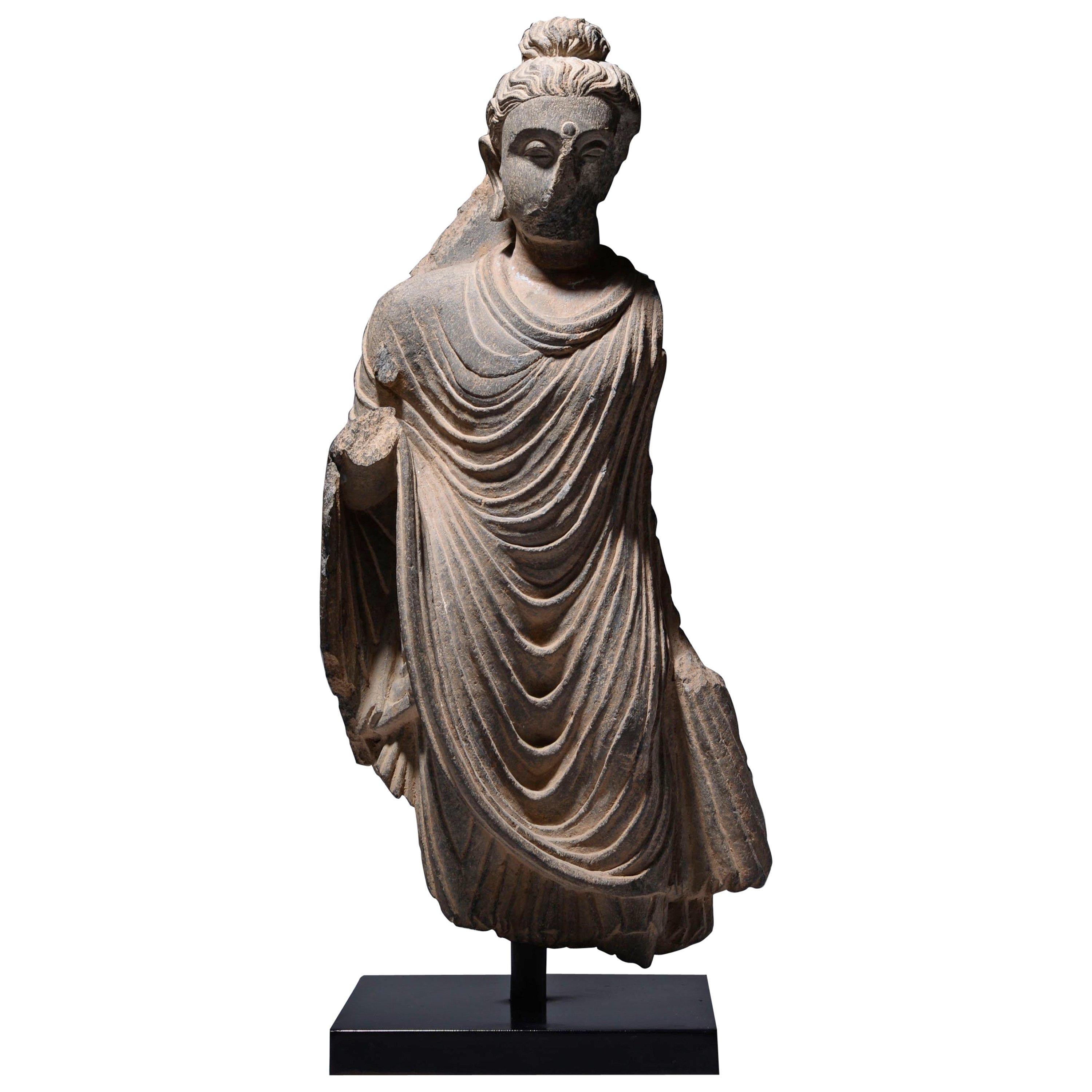 Gandharan Schist Buddha
Circa 3rd Century A.D.

This finely carved stone statue depicts the Buddha, clad in cascading folds of fabric, clinging lightly to the contours of his body; particular attention has been given to the hair and face, and his