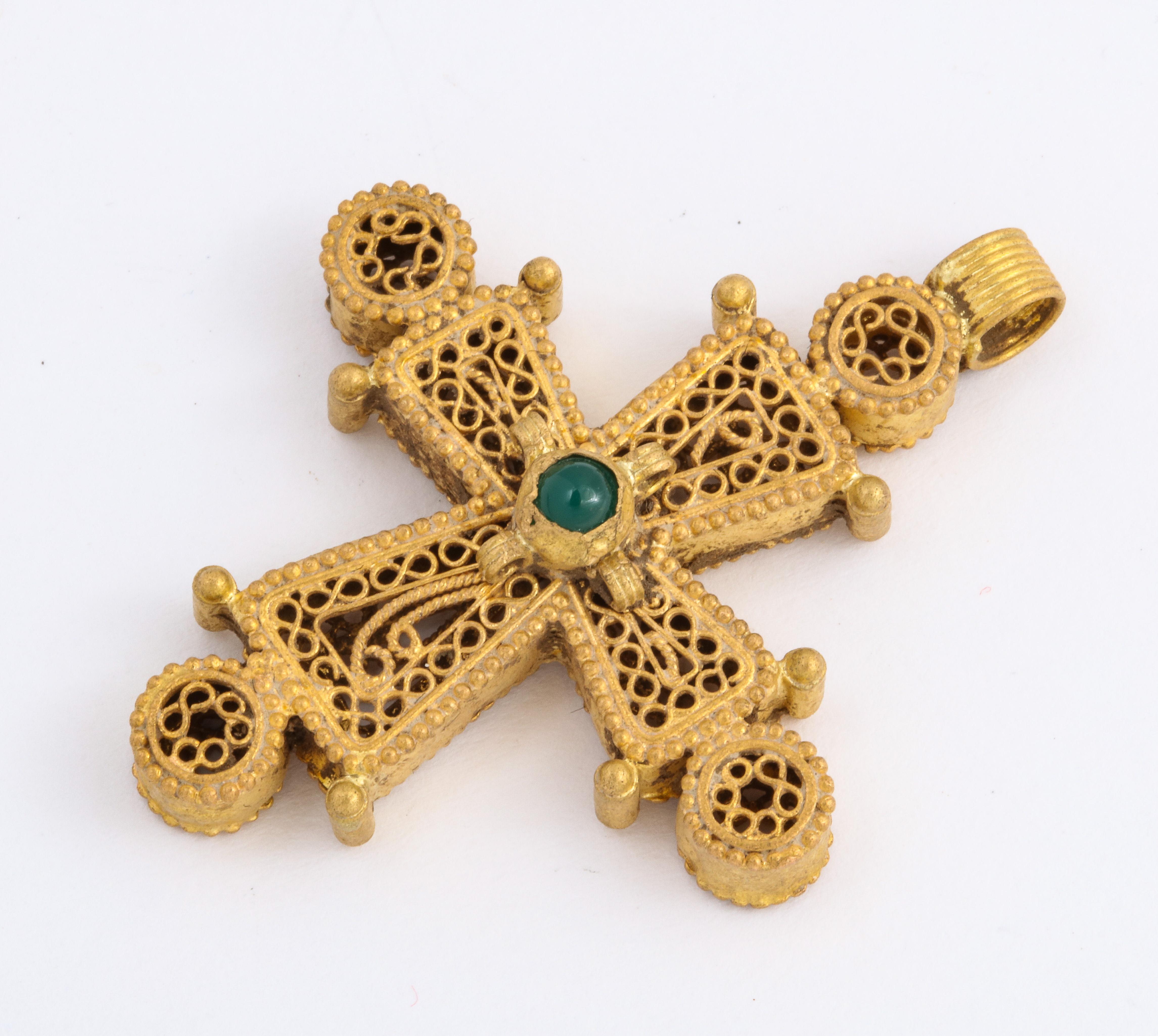 A high karat rare gold Byzantine cross with beautiful open work and circular scroll work is centered by an emerald of the same period. Tiny baubles of gold are placed at each cross end and round the gemstone. The cross was made approximately one