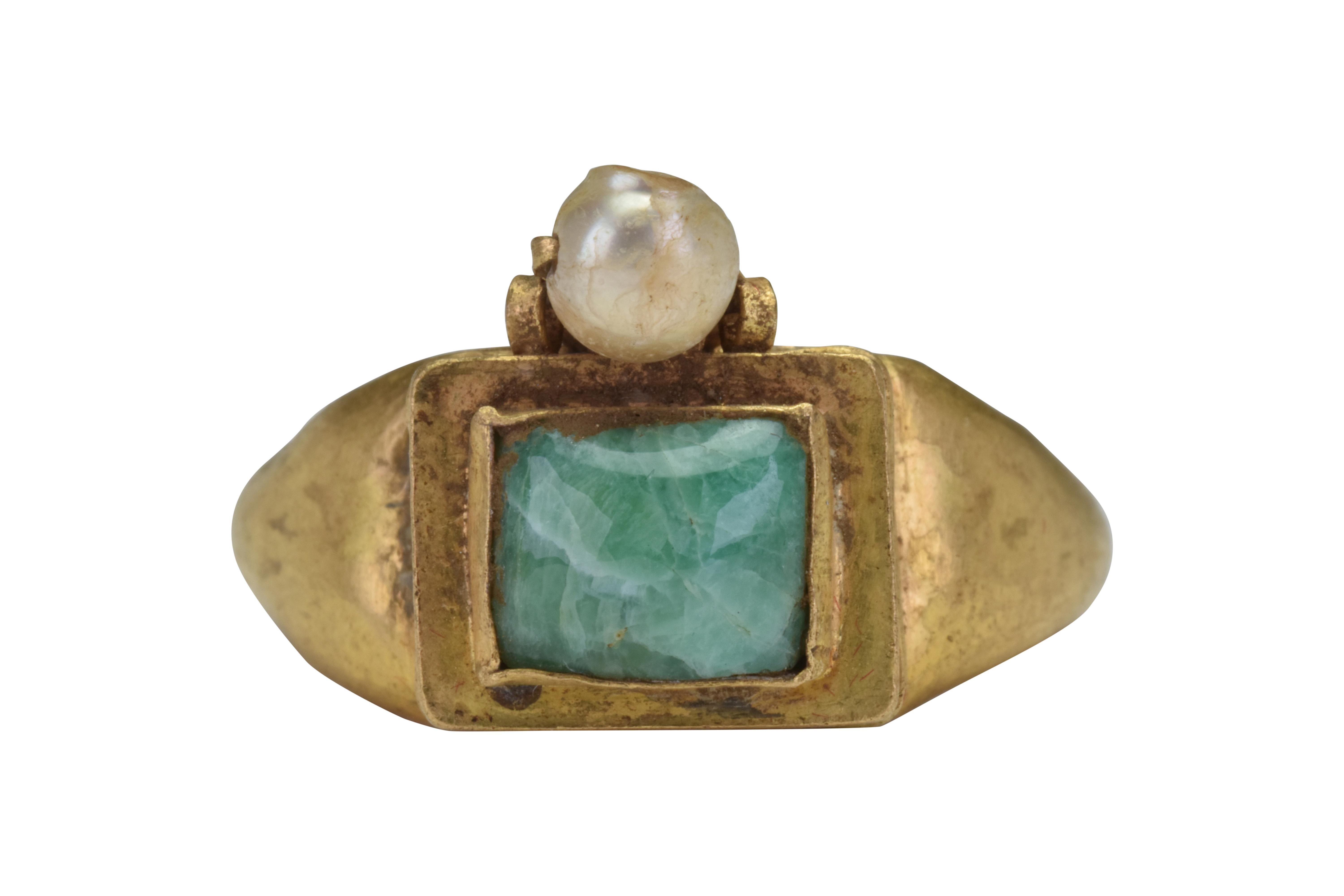 Byzantine Gold Ring with Emerald and Pearls 

Ca. 500-600 AD

A stunning gold finger ring of a smooth, round hoop with expanding shoulders to support a rectangular bezel with a banded base and tiered design embellished with an emerald cabochon.